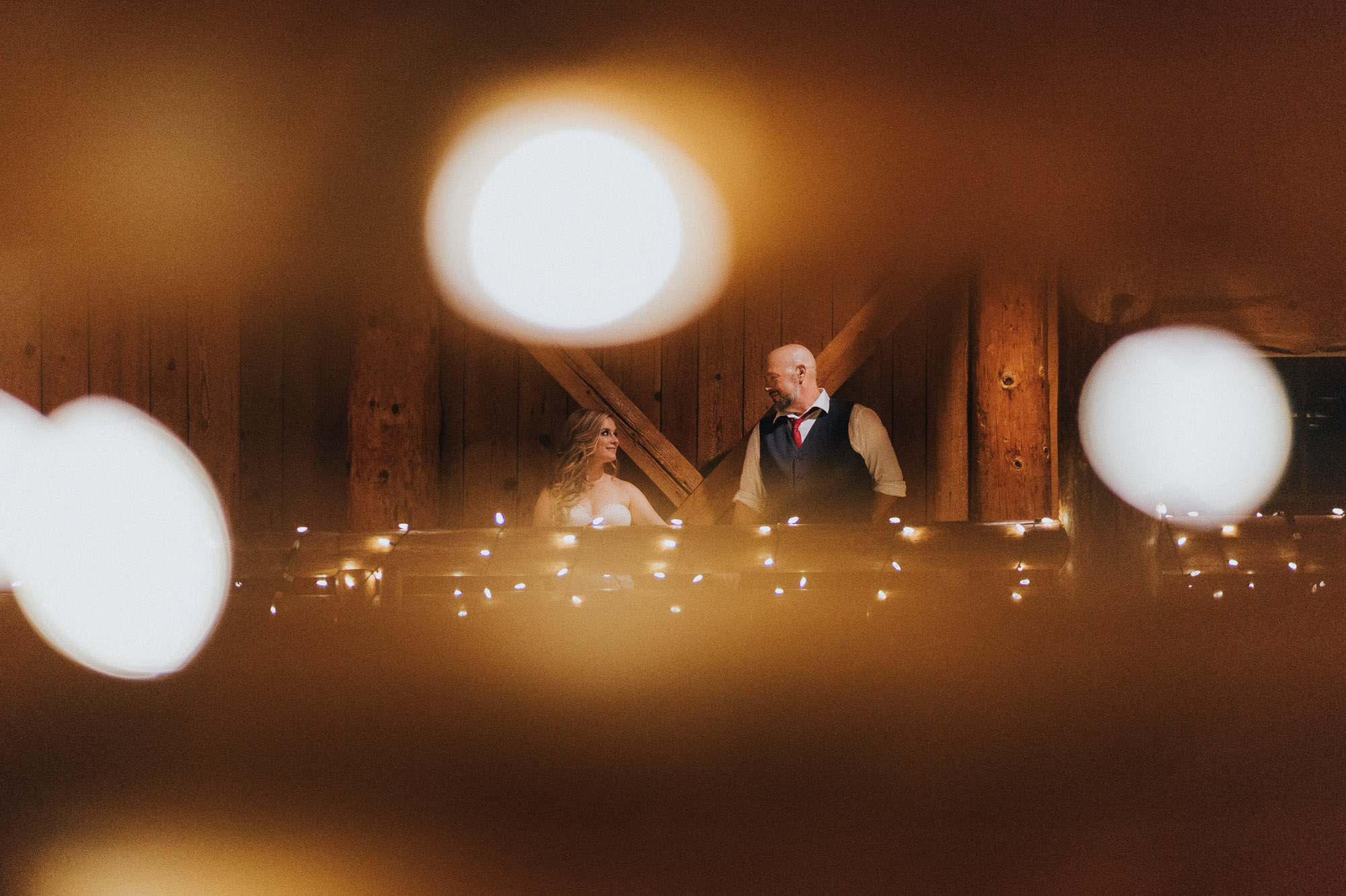 Marley and Kevin hold hands on the balcony of Sunriver's Great Hall, framed by twinkle lights