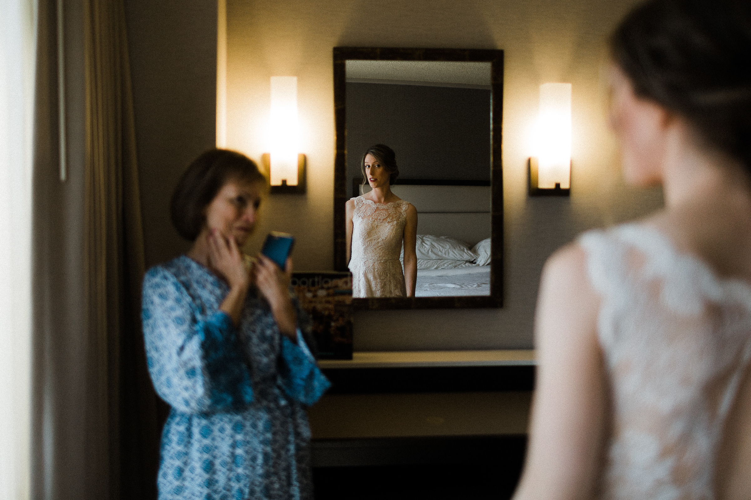 Bride looks at herself in mirror as mother looks on in Portland, Oregon
