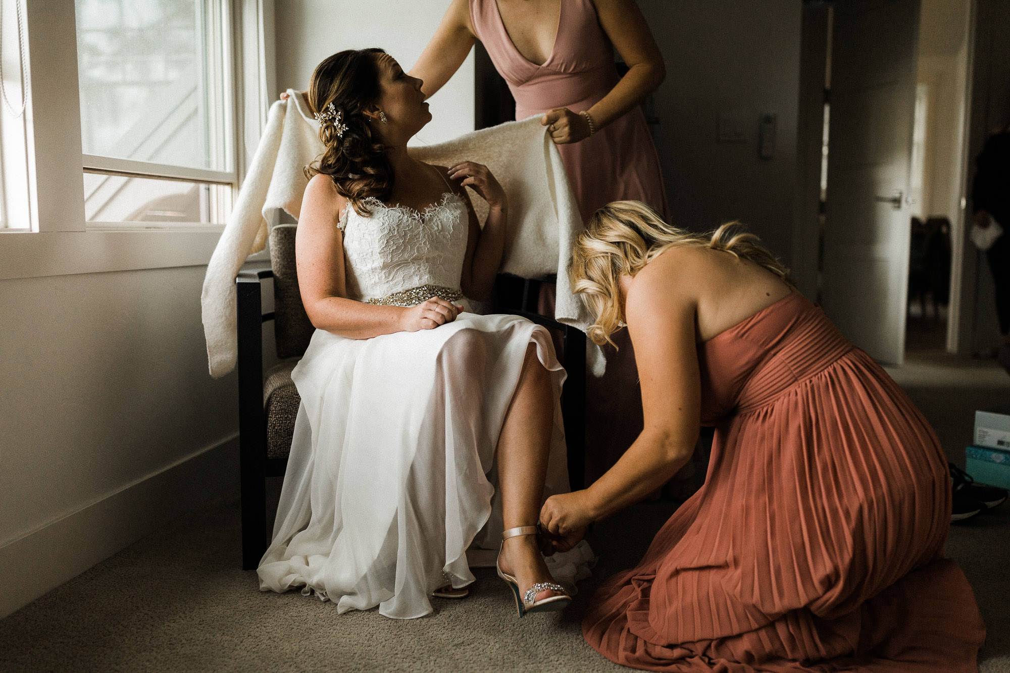 Bridesmaids help the bride get dressed at Tetherow Resort in Bend, Oregon