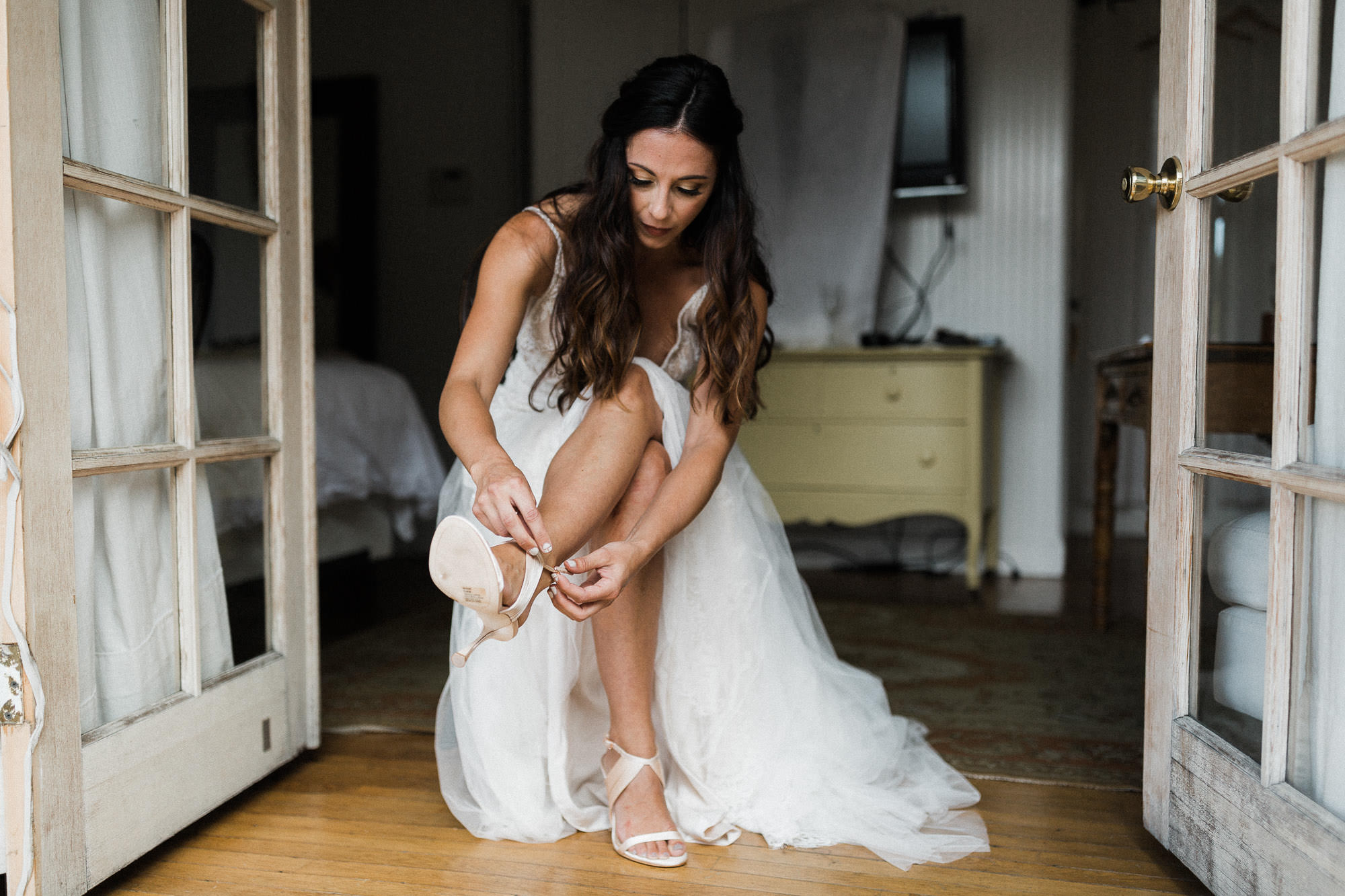 Bride puts on her shoes in the doorway of a cottage in Bend, Oregon
