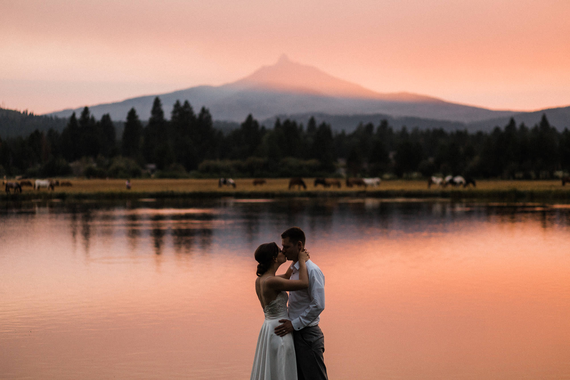 Bride and groom kiss with mountain view at sunset at Black Butte Ranch in Sisters, Oregon