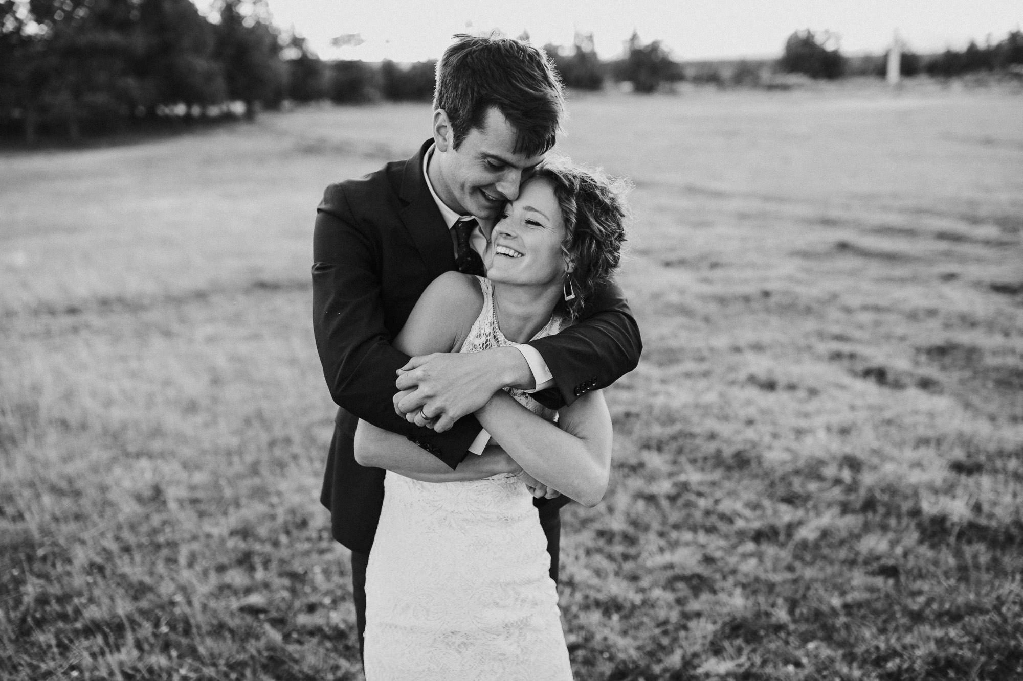 Bride and groom embrace in a field in Redmond, Oregon