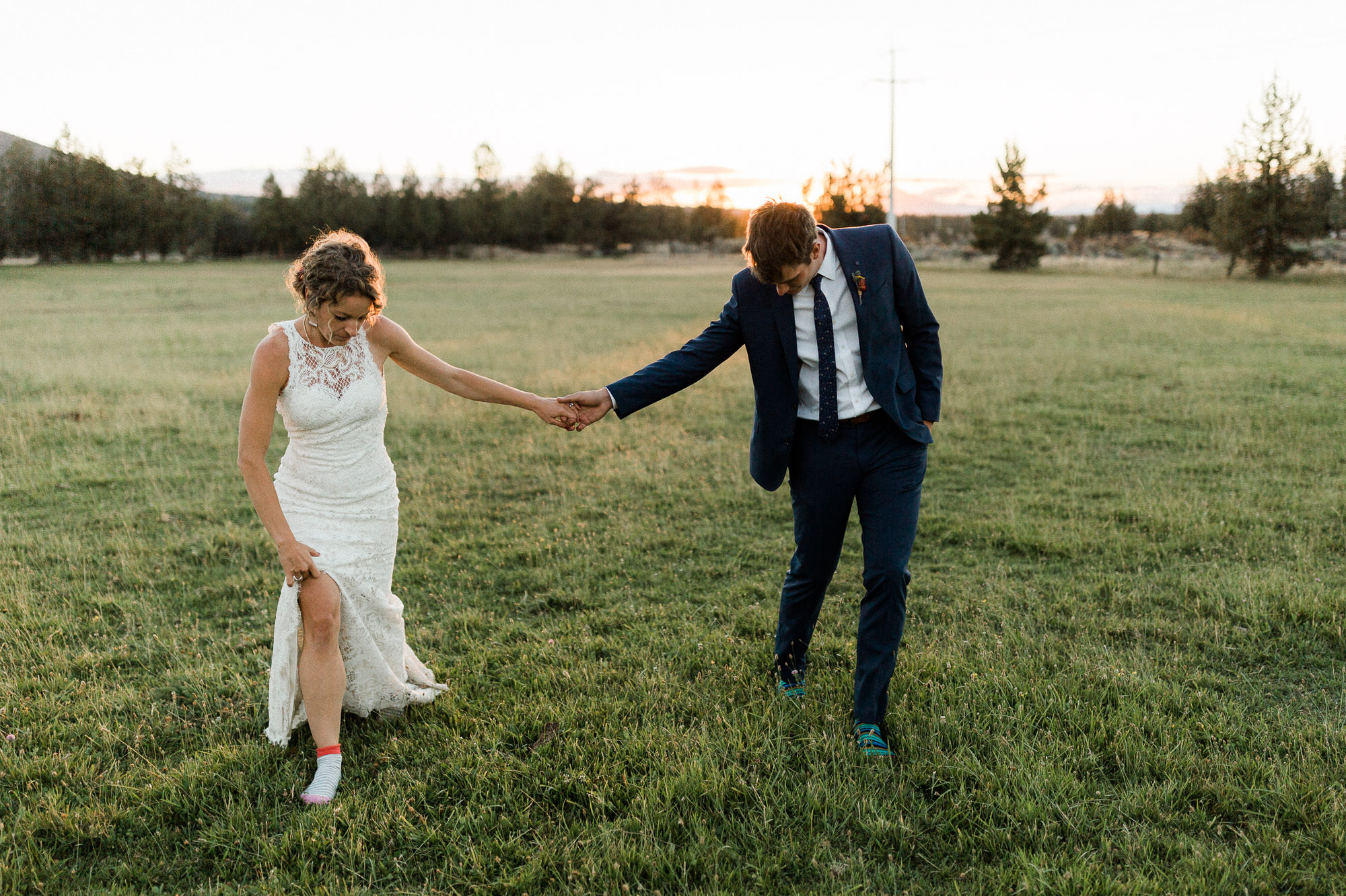 Bride and groom walk through a field in socks in Redmond, Oregon