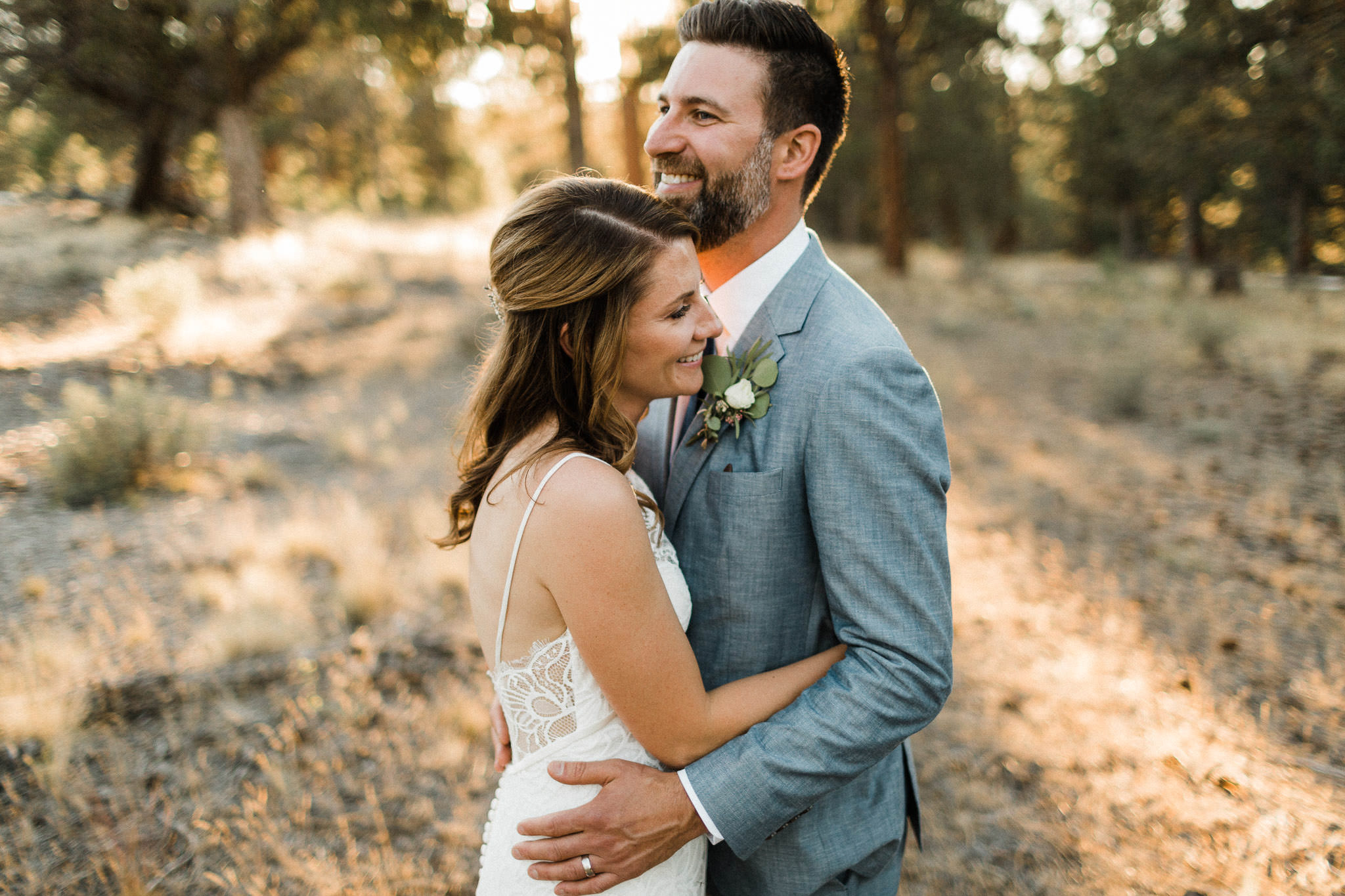 Bride and groom laugh and embrace in a field at Rock Springs Ranch in Bend, Oregon