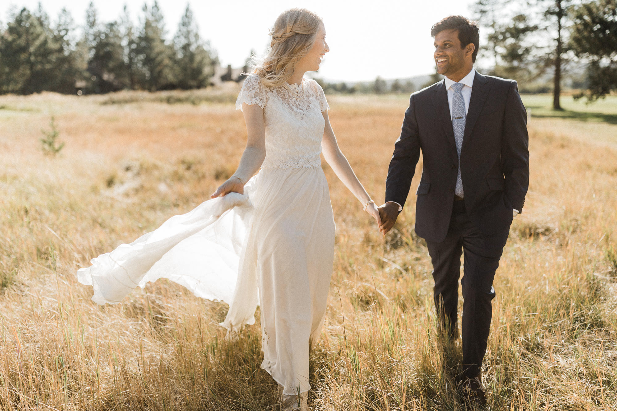 Bride and groom walk through a field in Sunriver, Oregon