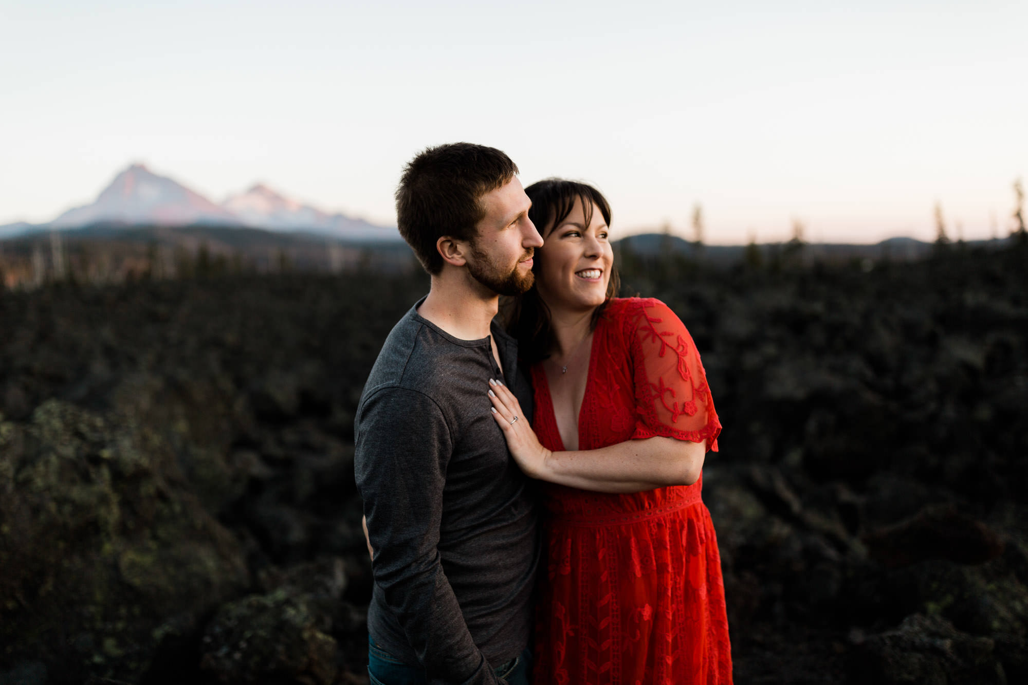 A couple embraces in front of a mountain view on McKenzie Pass in Oregon