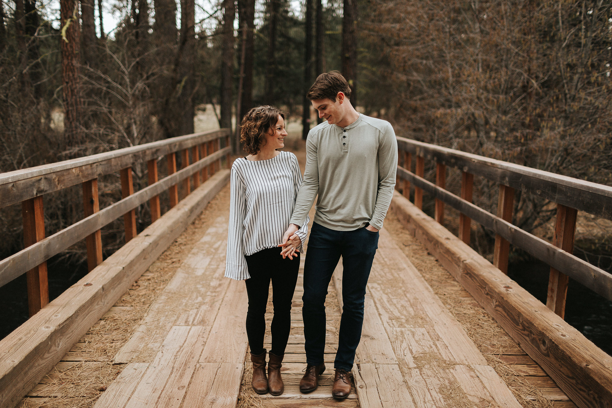 Couple hold hands on a wooden bridge over the Metolius River in Sisters, Oregon