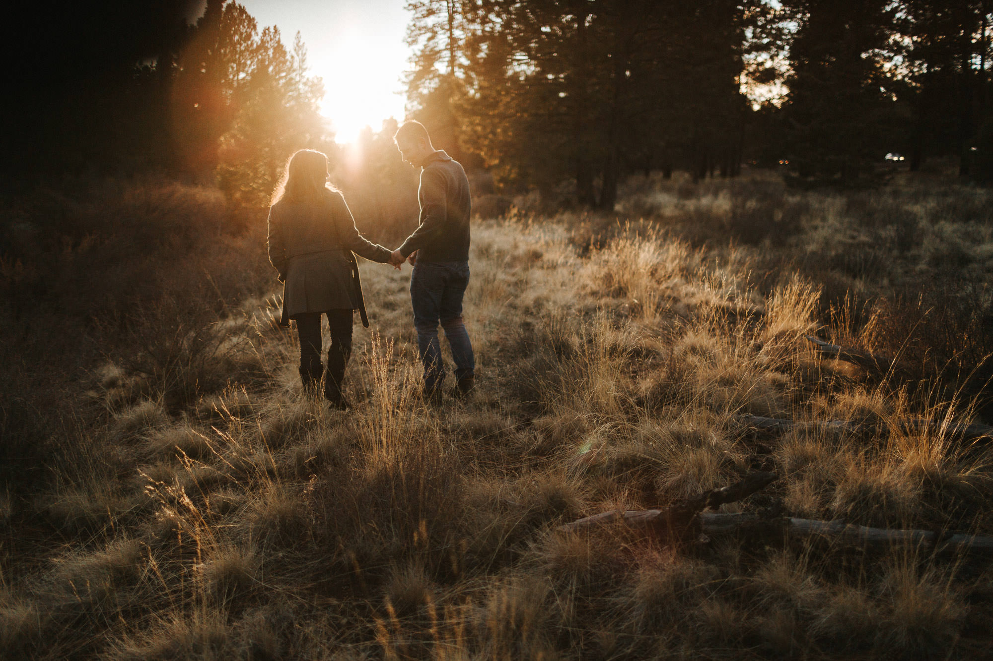 Couple walks through a field at sunset in Bend, Oregon