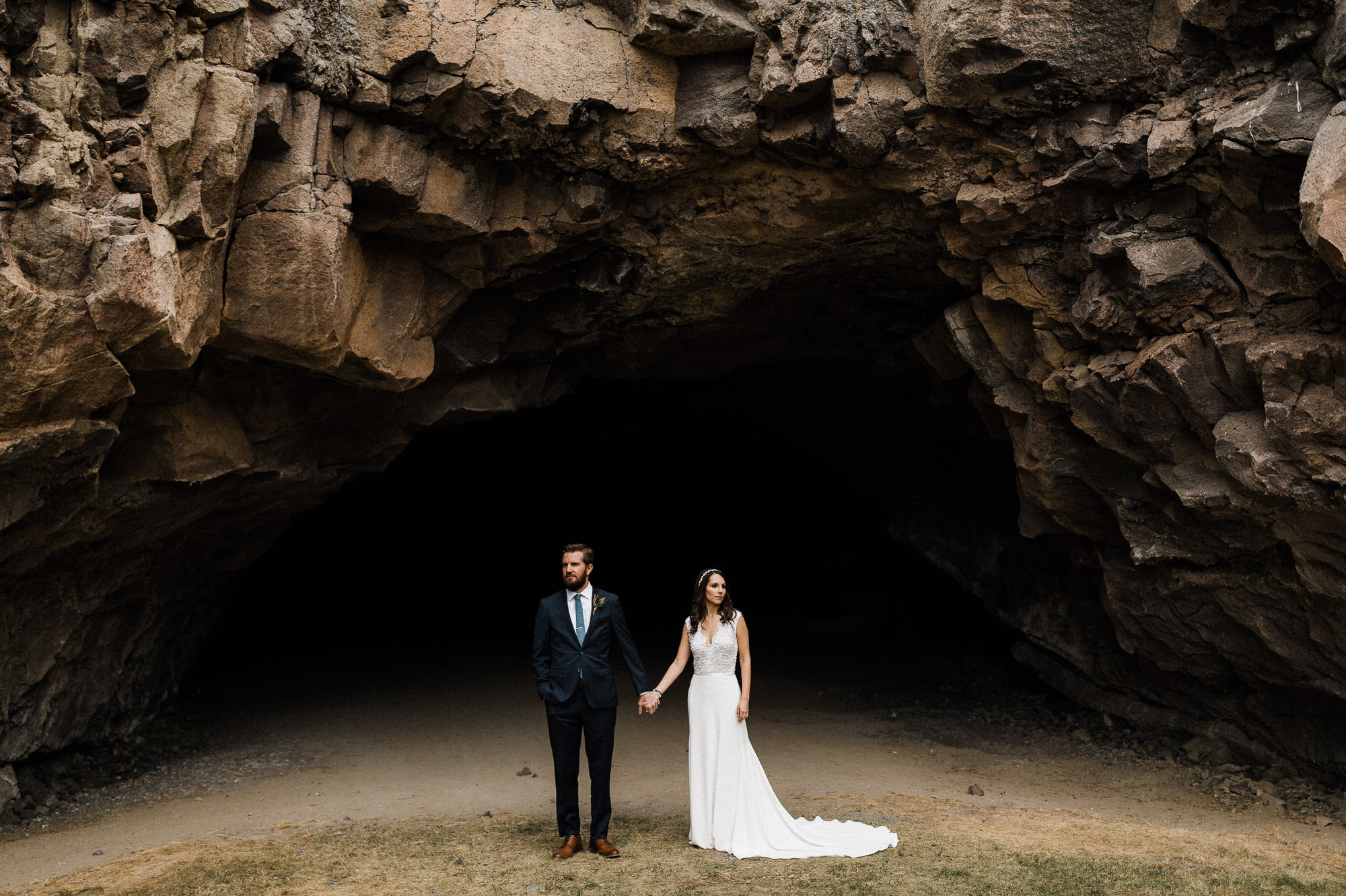 A couple holds hands at the entrance of a cave at Pronghorn Resort in Bend, Oregon