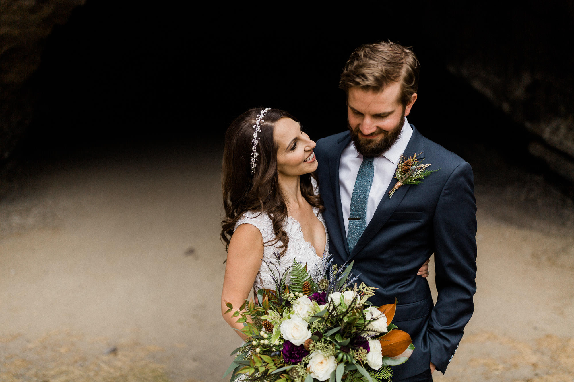 Bride and groom laugh at the entrance to a cave at Pronghorn Resort in Bend, Oregon
