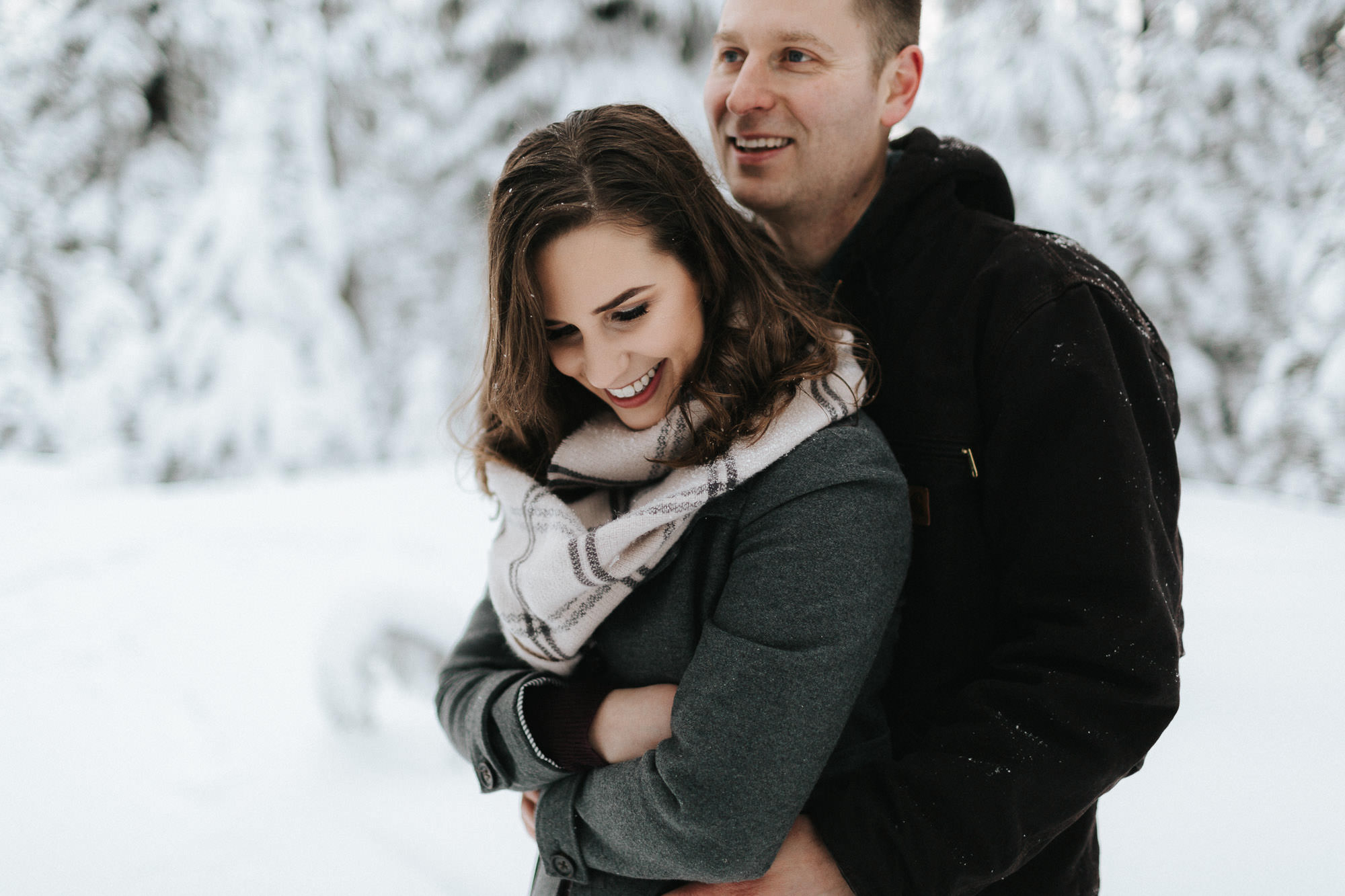 Couple embrace in snowy forest in Bend, Oregon