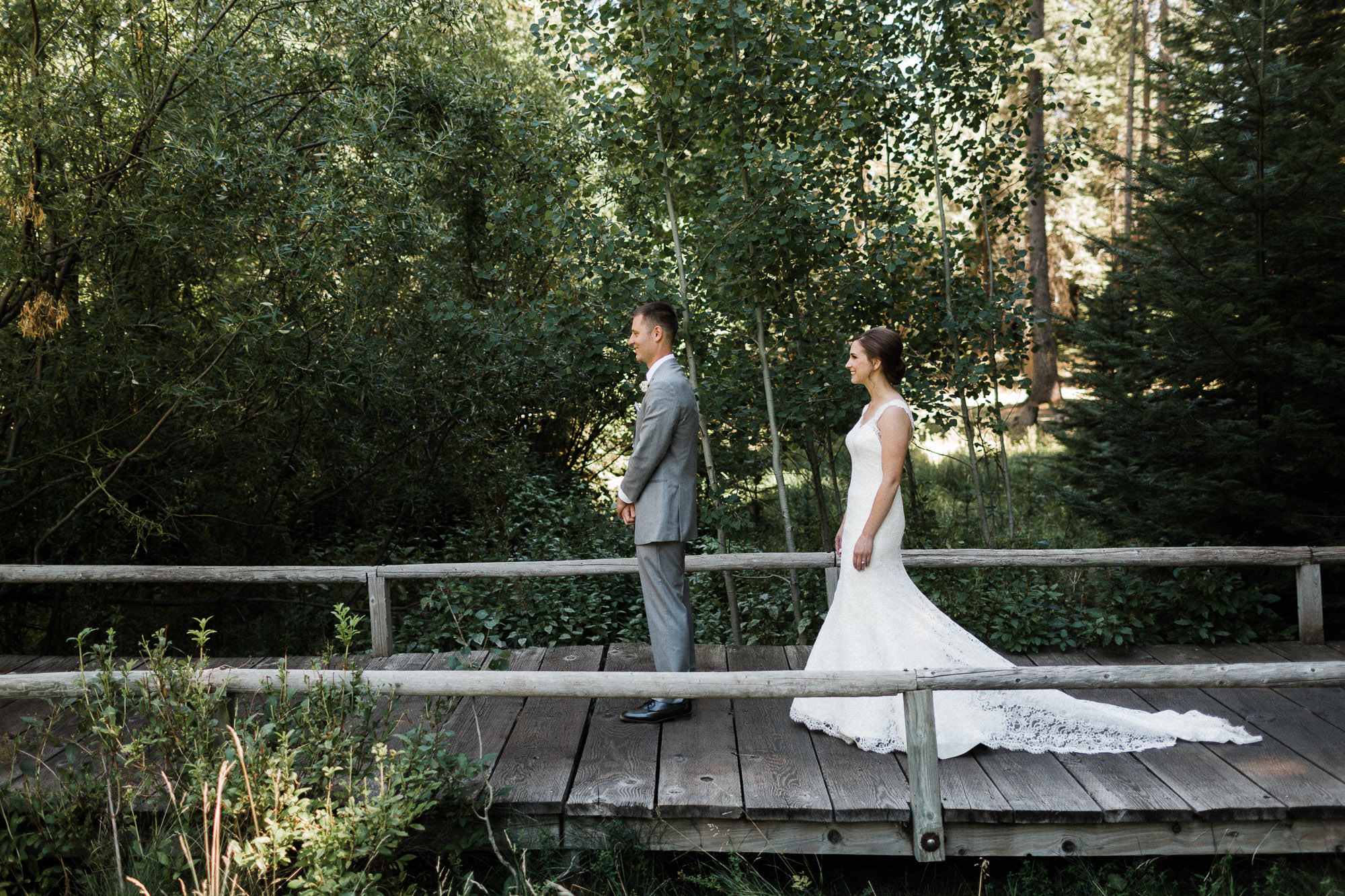 Bride approaches groom for their first look on a boardwalk in the forest at Black Butte Ranch