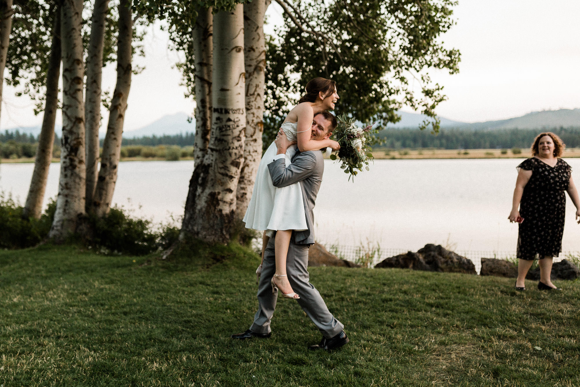 Groom lifts bride off the ground as she laughs at Black Butte Ranch