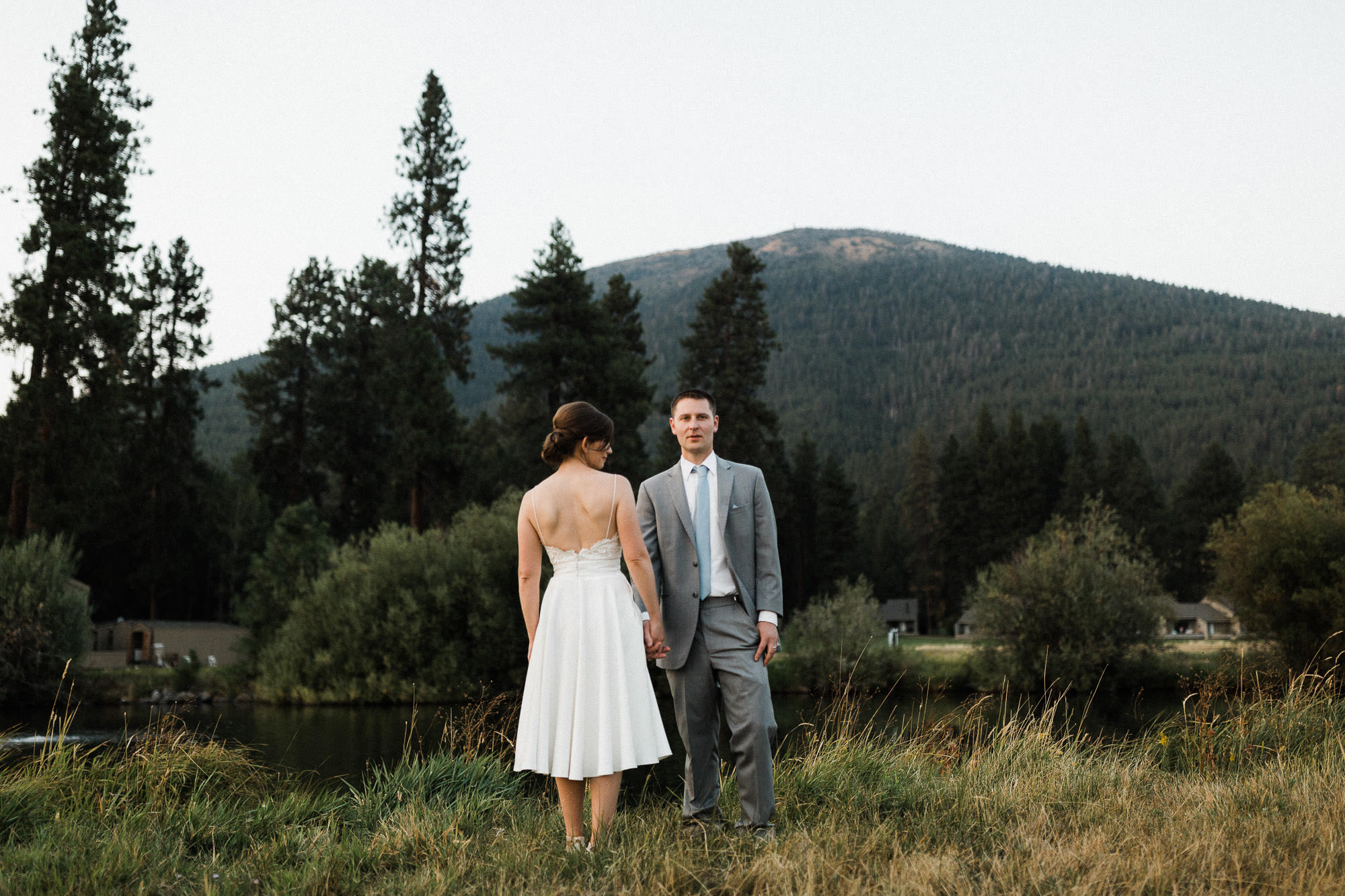 Bride and groom pose in a field with Black Butte in the background