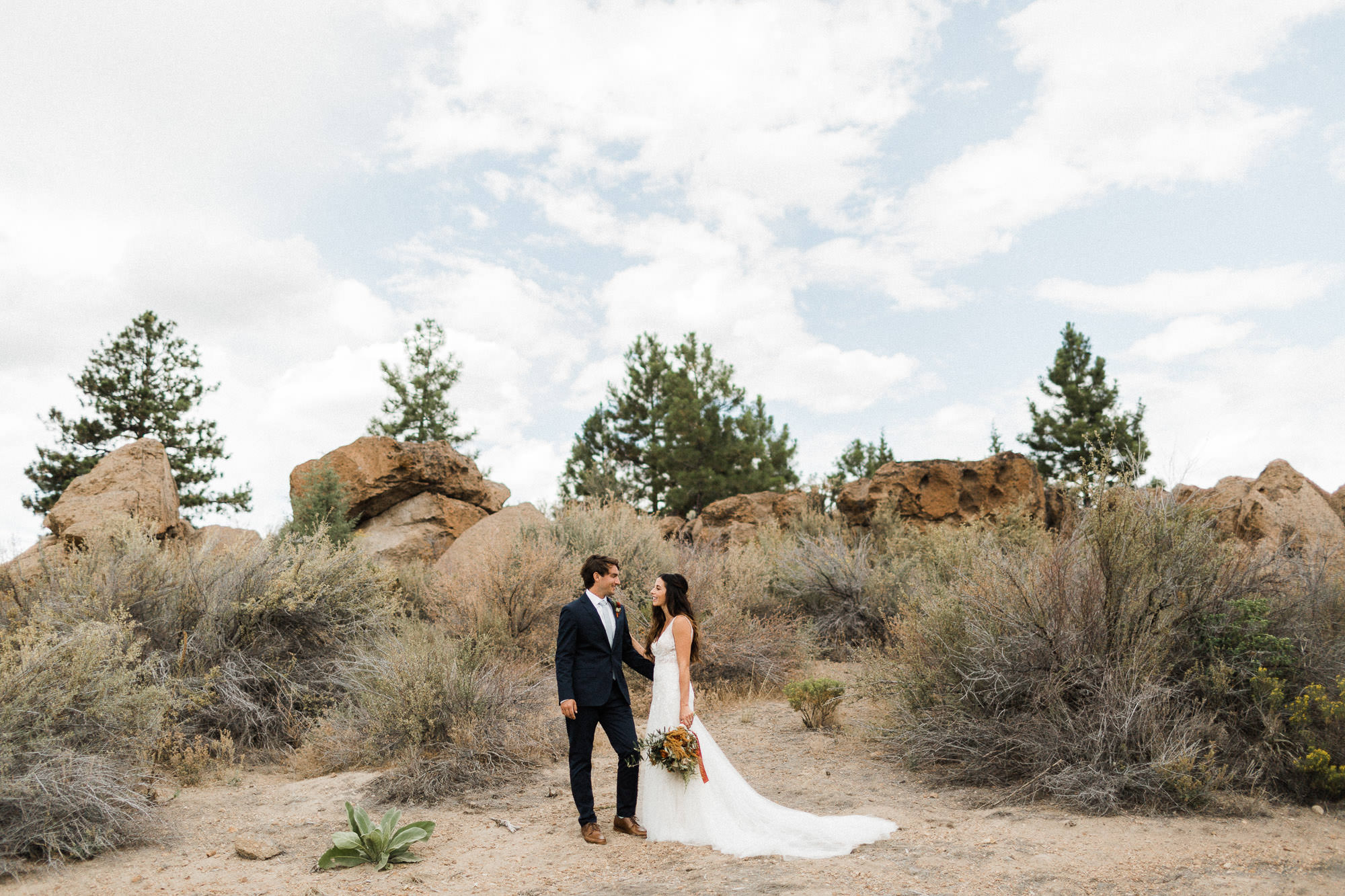 Bride and groom pose in the desert at Broken Top Club in Bend, Oregon
