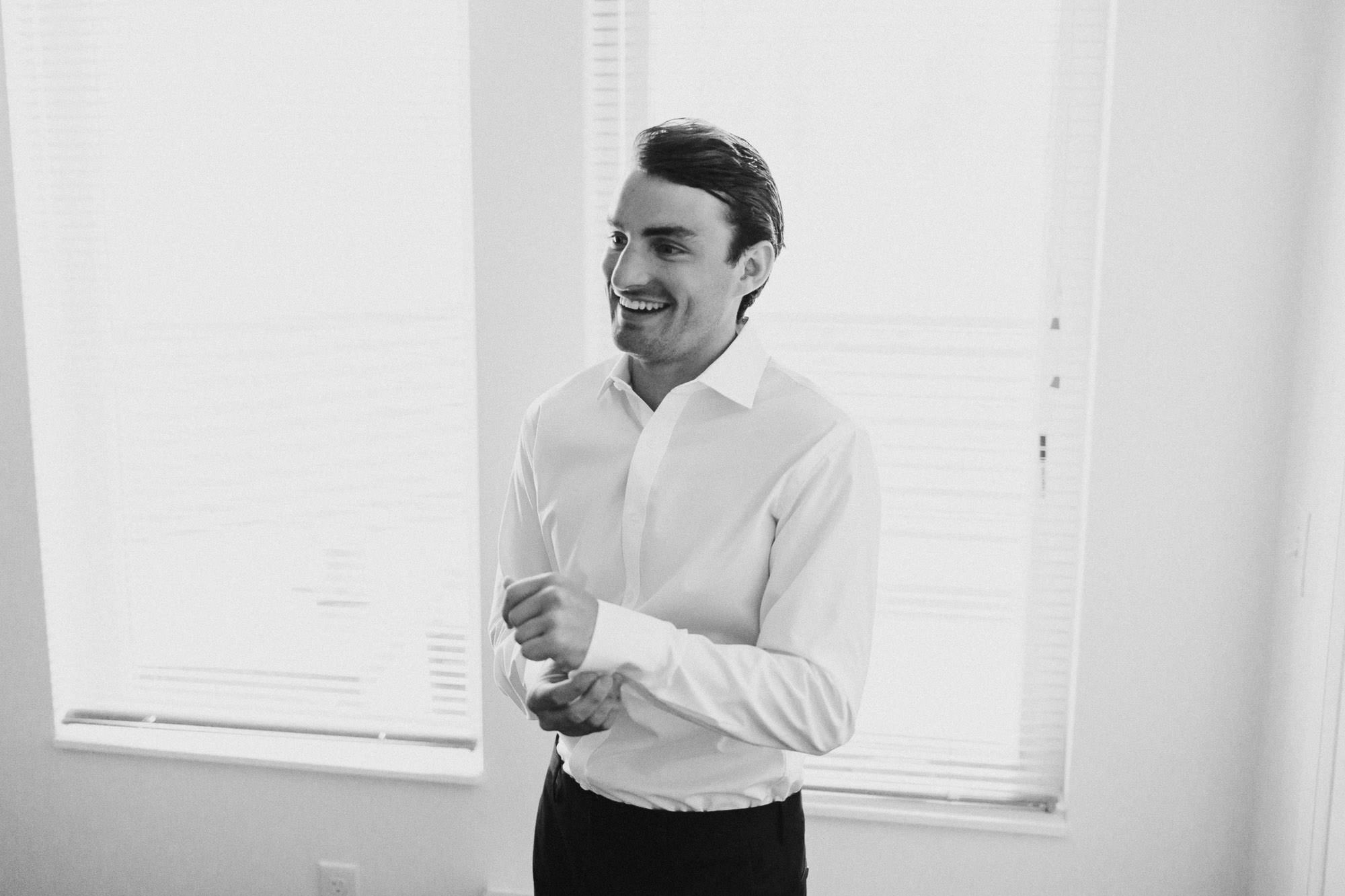 Groom smiling, buttoning his cuff in Bend, Oregon