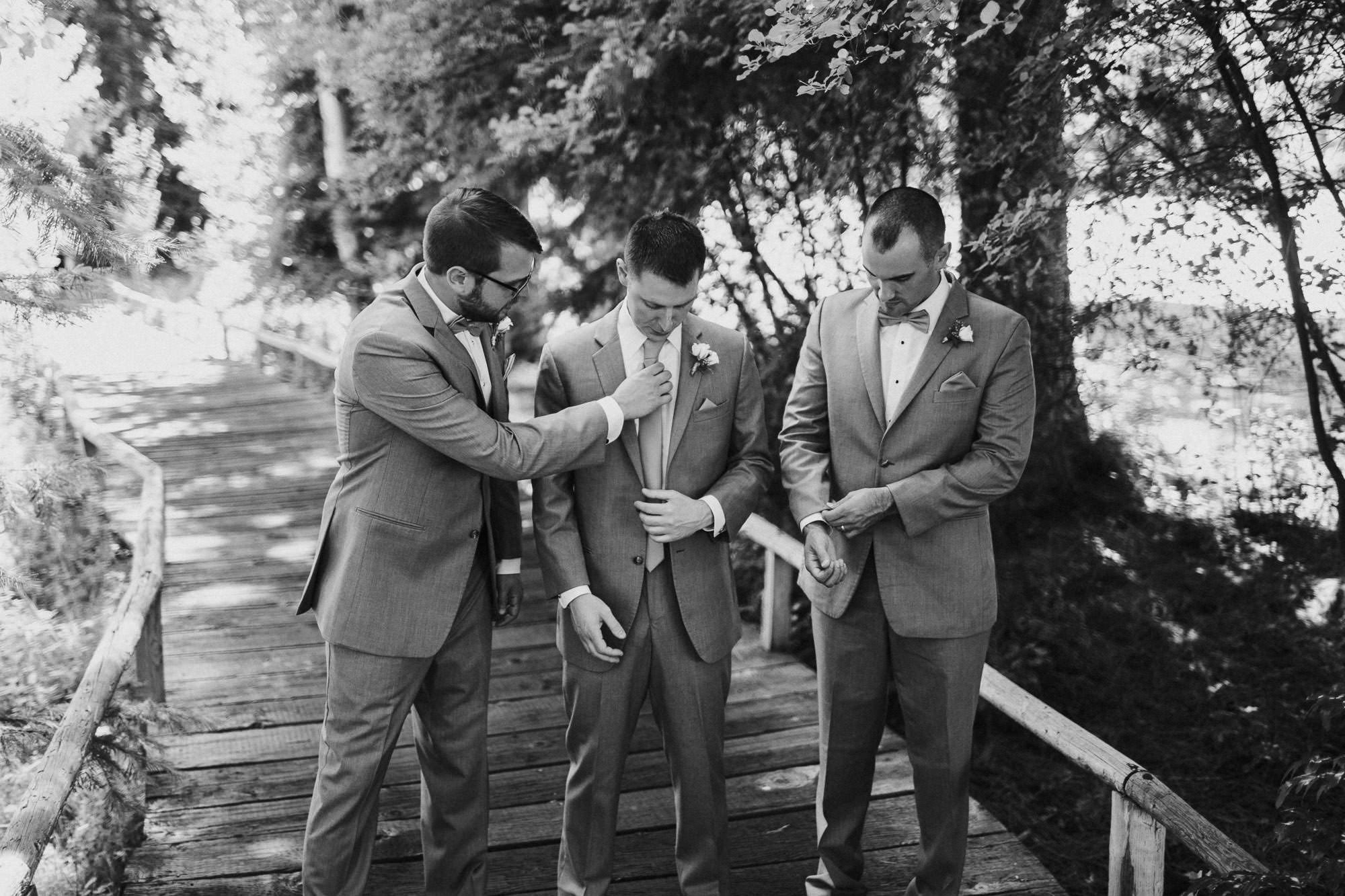 Groomsmen help groom adjust his tie at Black Butte Ranch