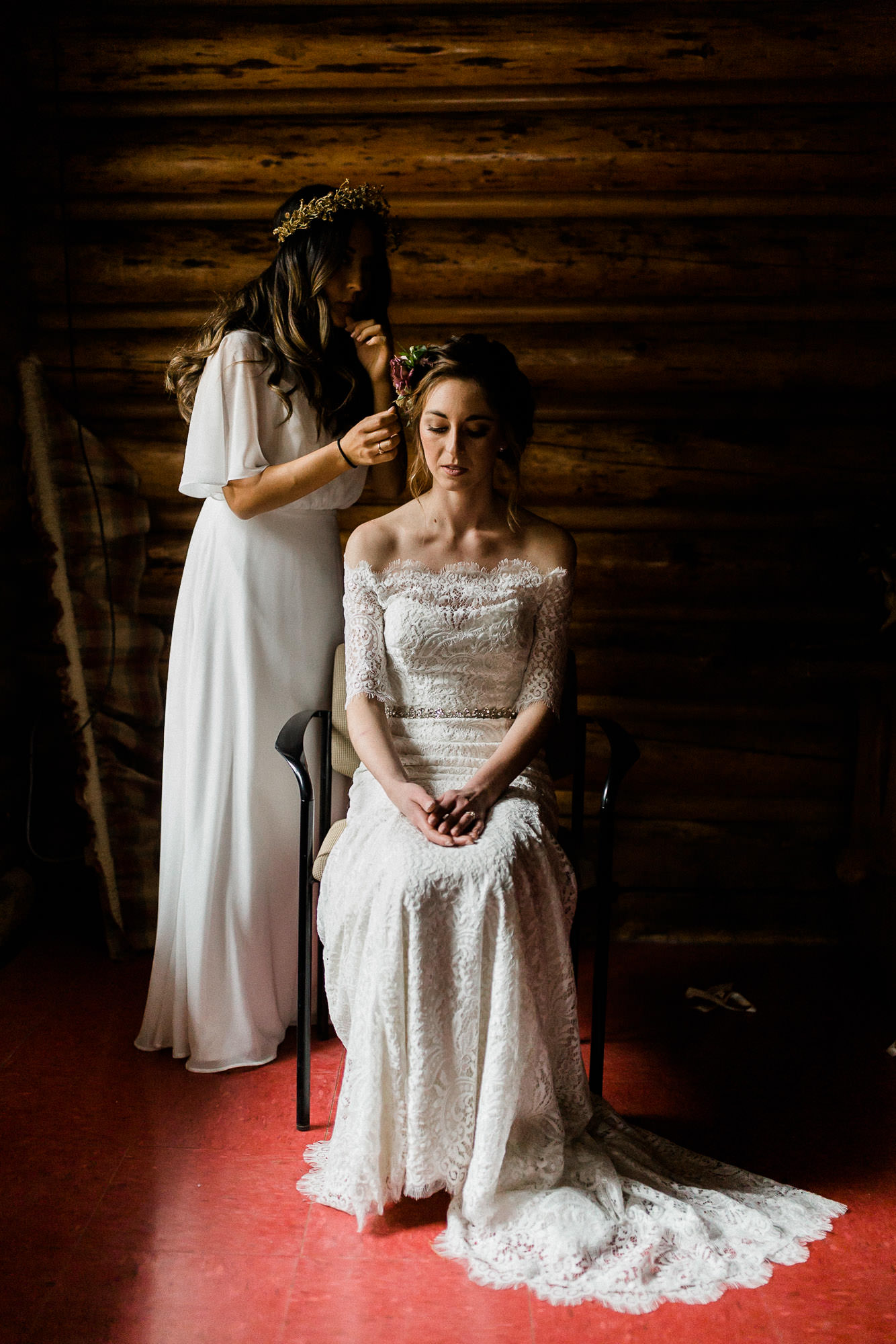 Maid of honor places floral hairpiece in bride's hair at Skyliner Lodge