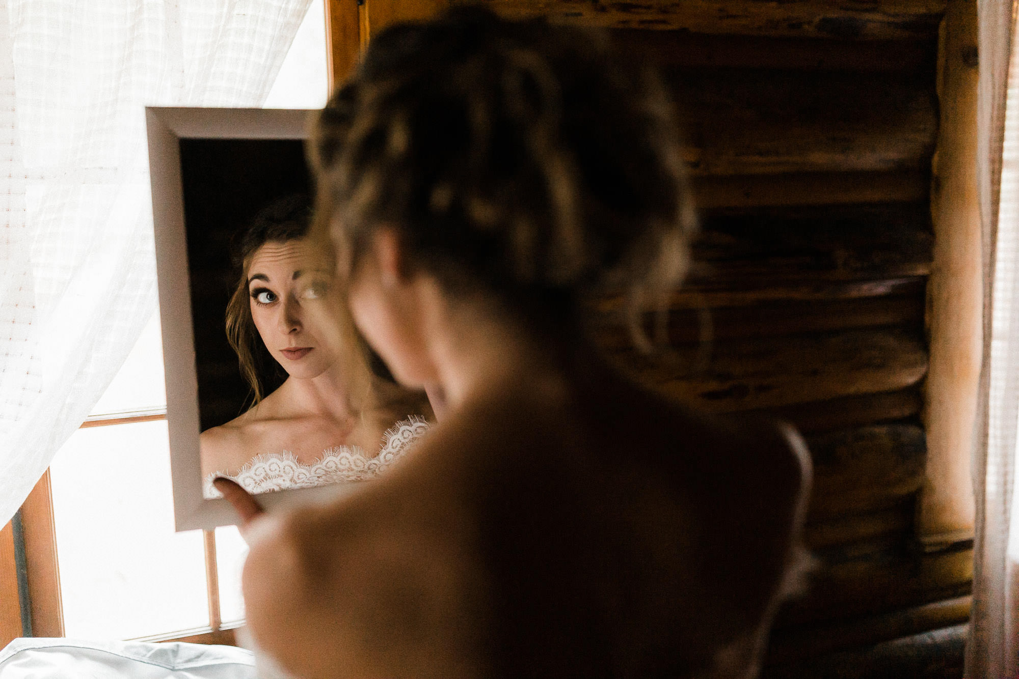 Bride looks at herself in a mirror at Skyliner Lodge in Bend, Oregon