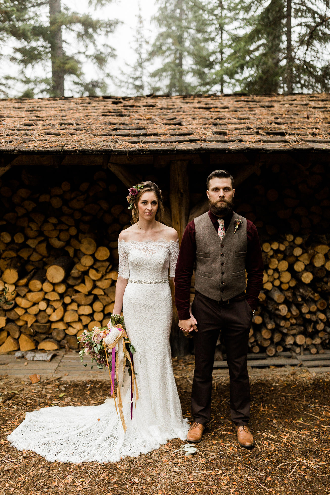 Bride and groom pose for portraits in front of firewood shed at Skyliner Lodge