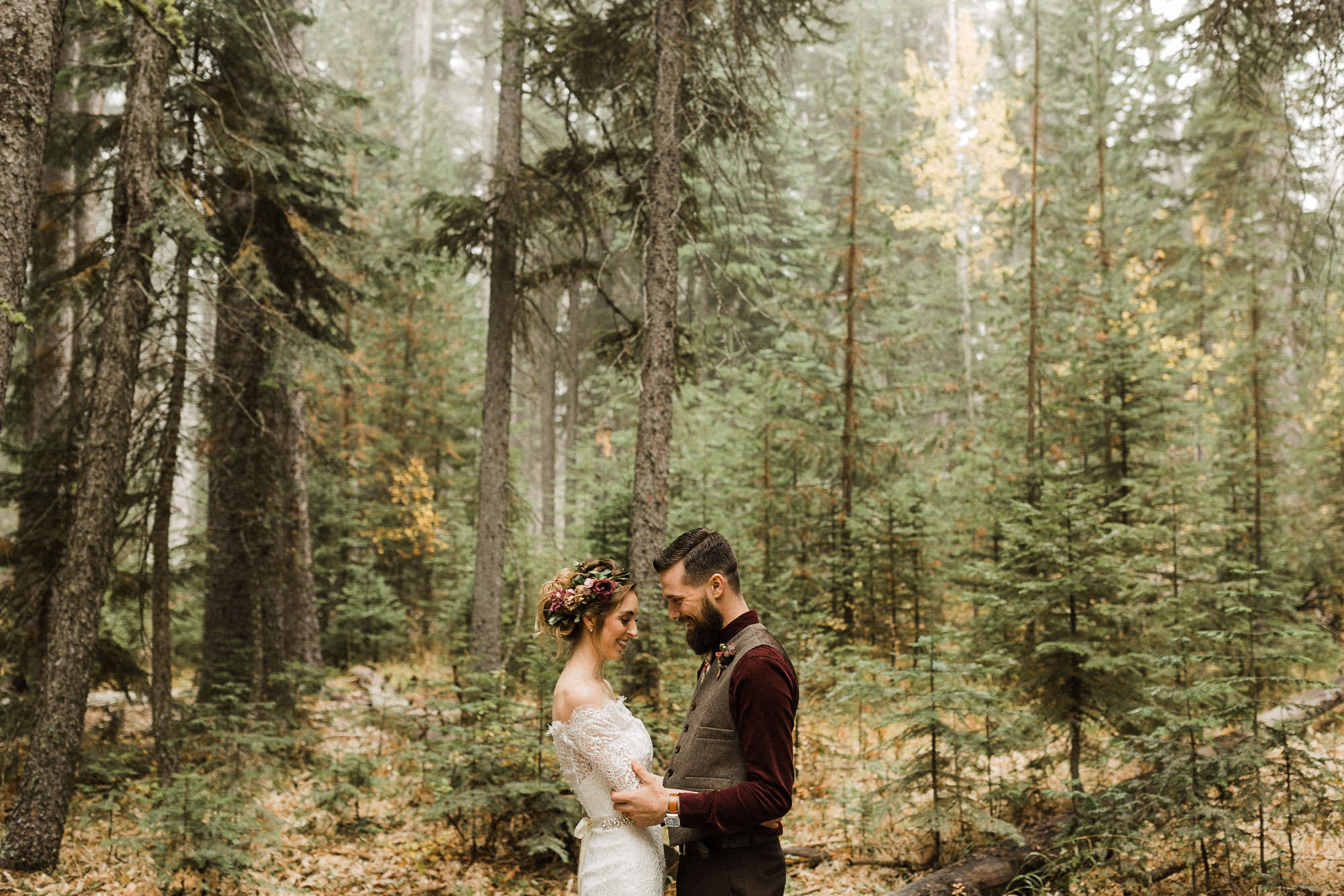 Bride and groom pose in the forest at Skyliner Lodge