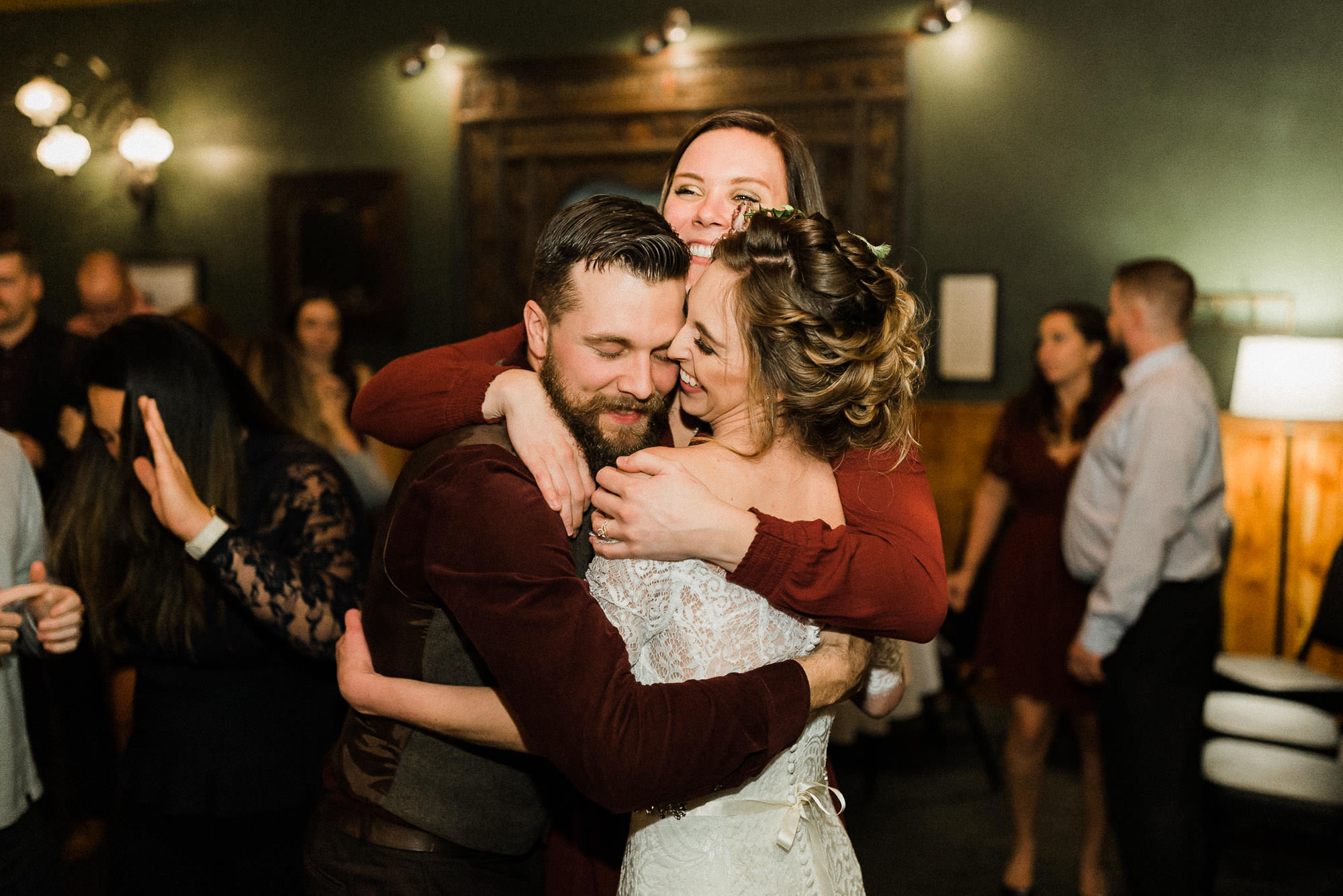 Bride, groom, and guest hug at McMenamin's Old St. Francis School in Bend, Oregon