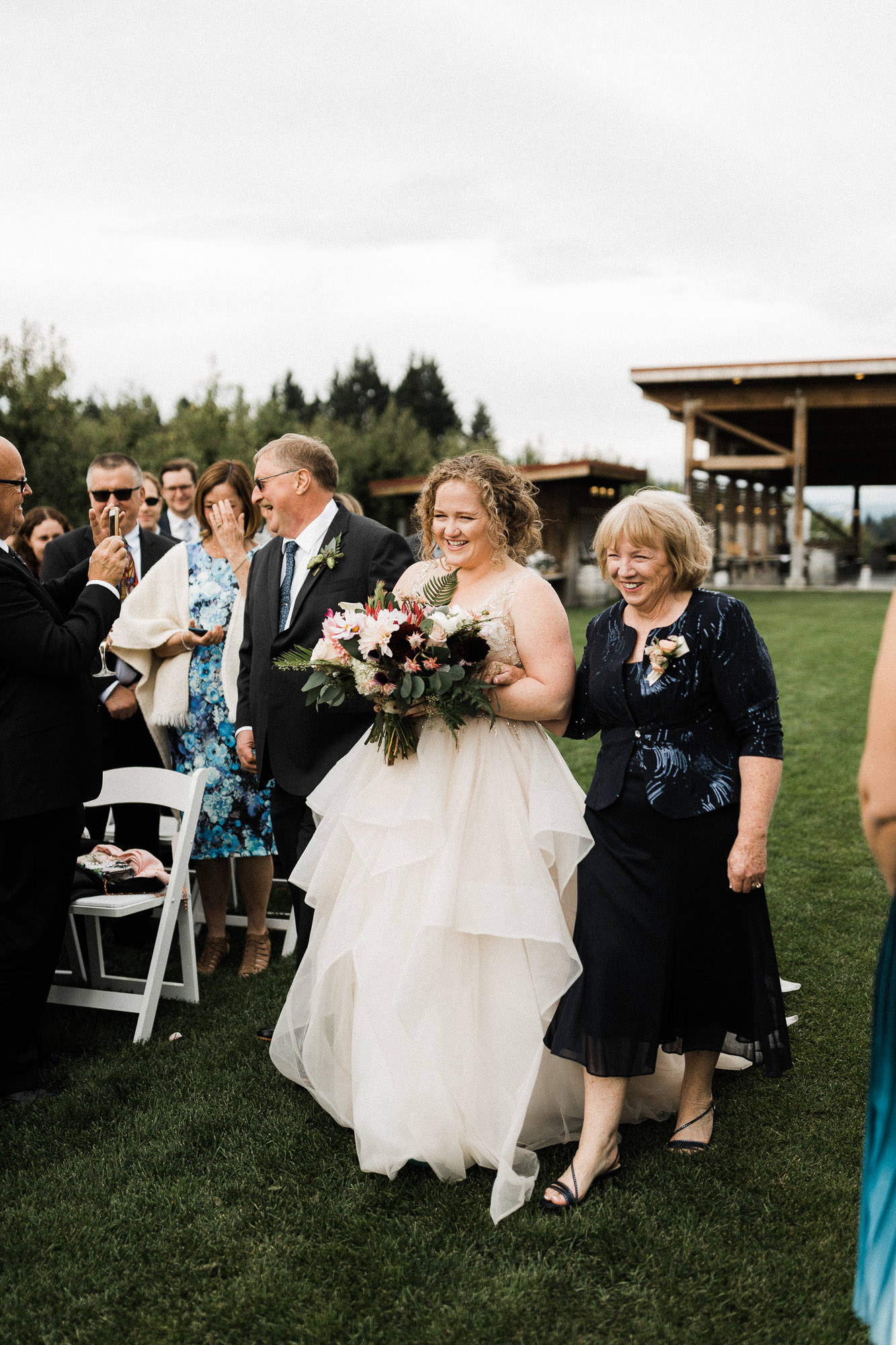 The bride's parents walk her down the aisle at Mt. View Orchards in Mt Hood, Oregon.