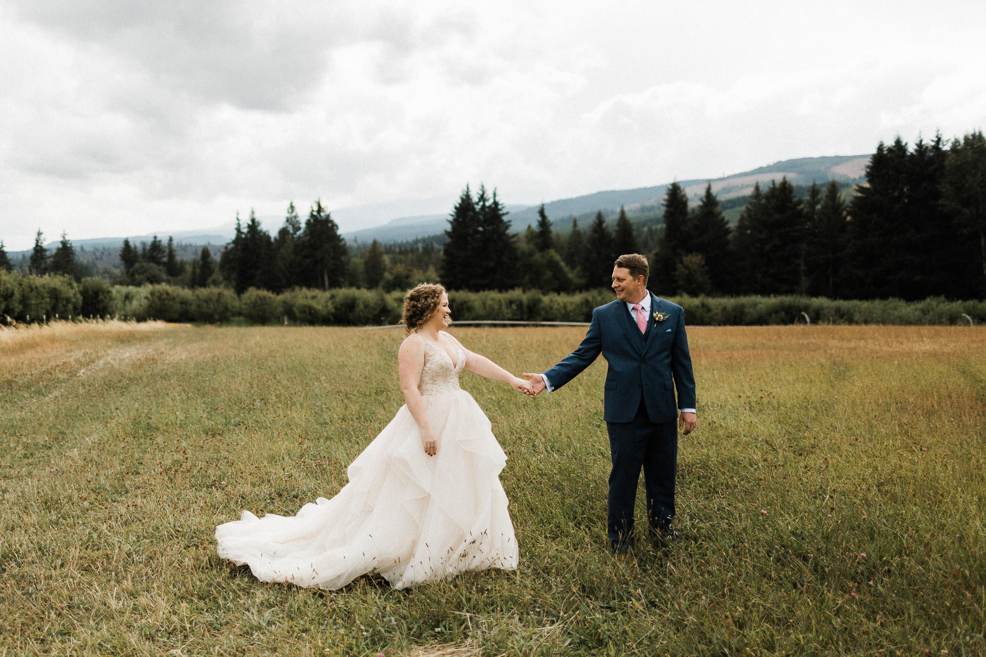 Bride and groom hold hands in a field at Mt. View Orchards in Mt Hood, Oregon 