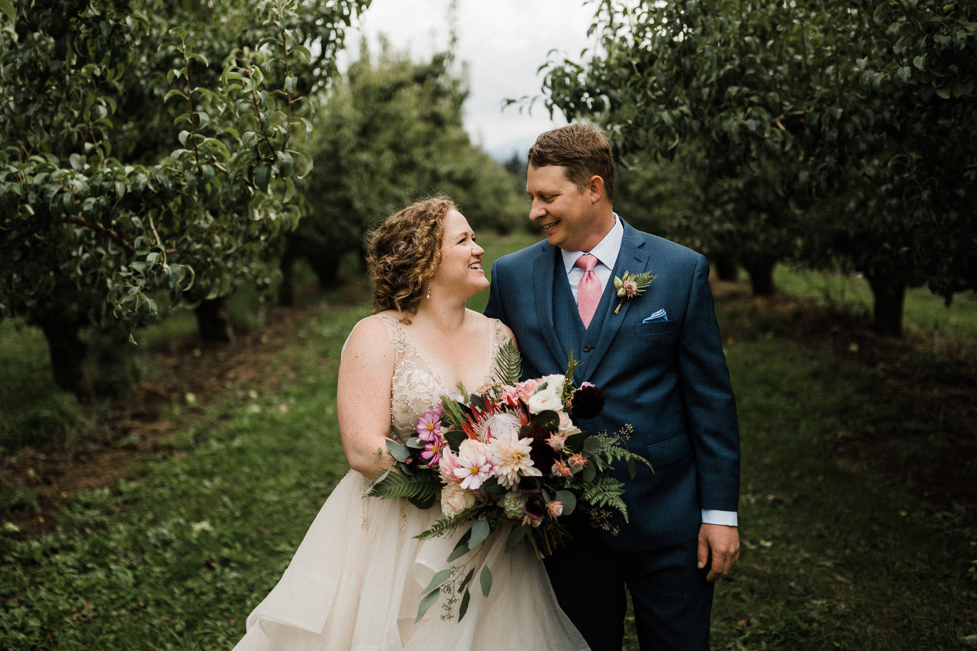 Bride and groom look at each other and laugh at Mt. View Orchards near Hood River, Oregon.