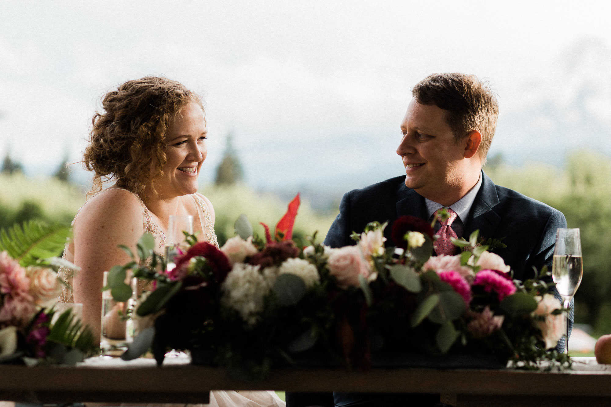 The bride and groom smile while guests give toasts at Mt. View Orchards in Oregon.