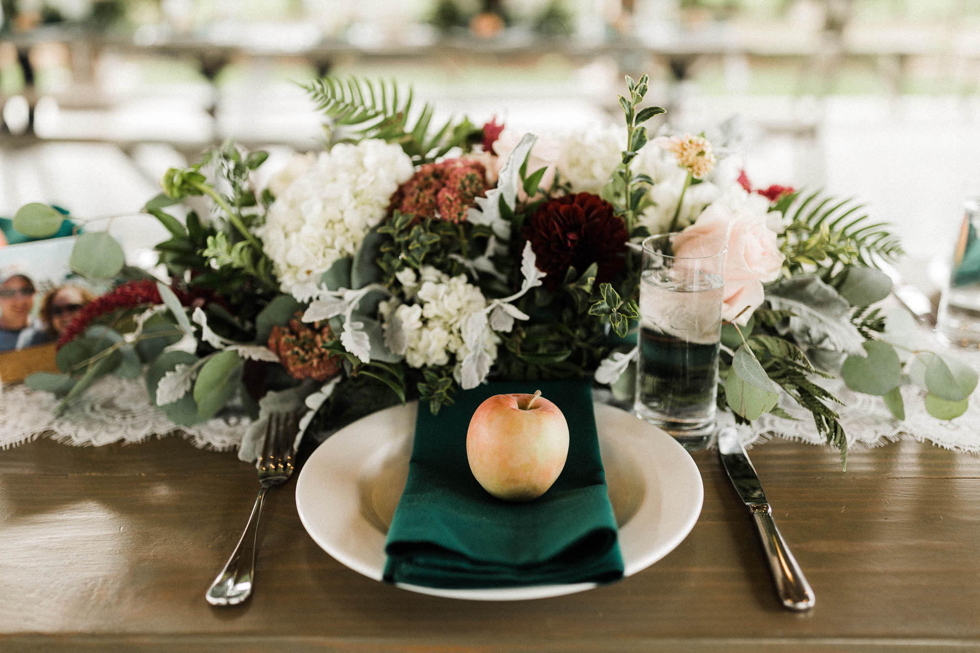 An apple adorns a place setting, with a floral arrangement behind it, at a farm-style table at Mt. View Orchards.