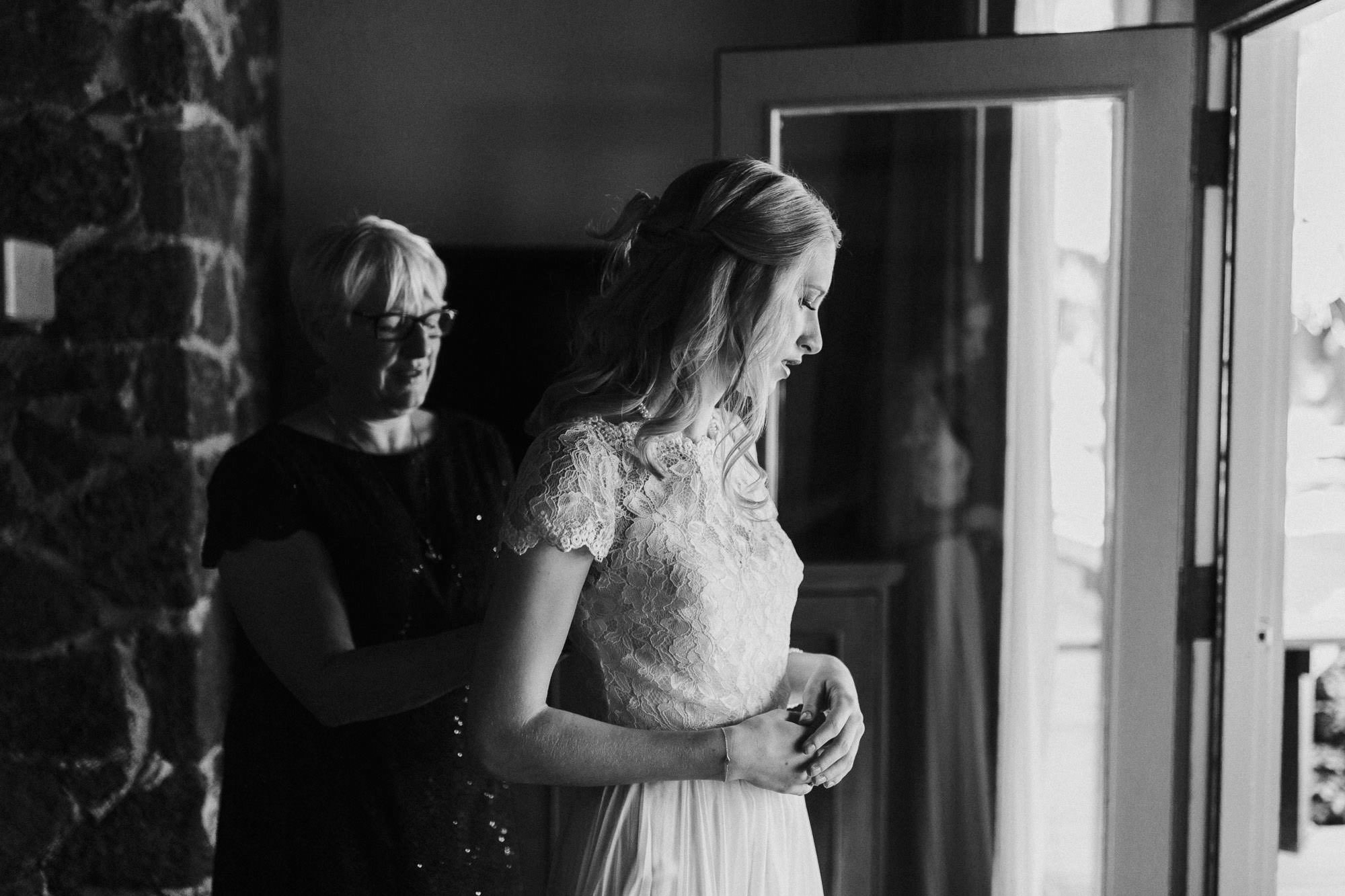 The bride's mother helps button up the bride's dress in Sunriver Oregon.