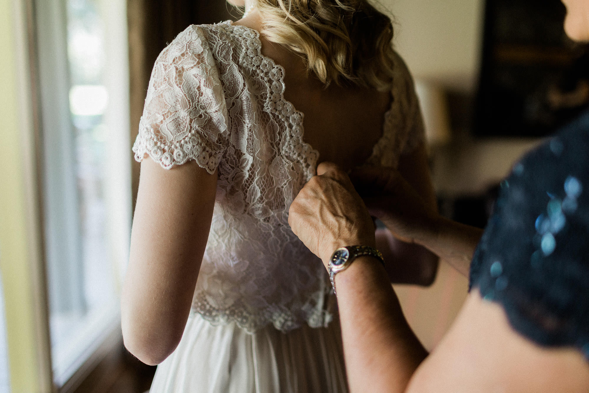 The bride's mother helps button up the bride's dress in Sunriver Oregon.