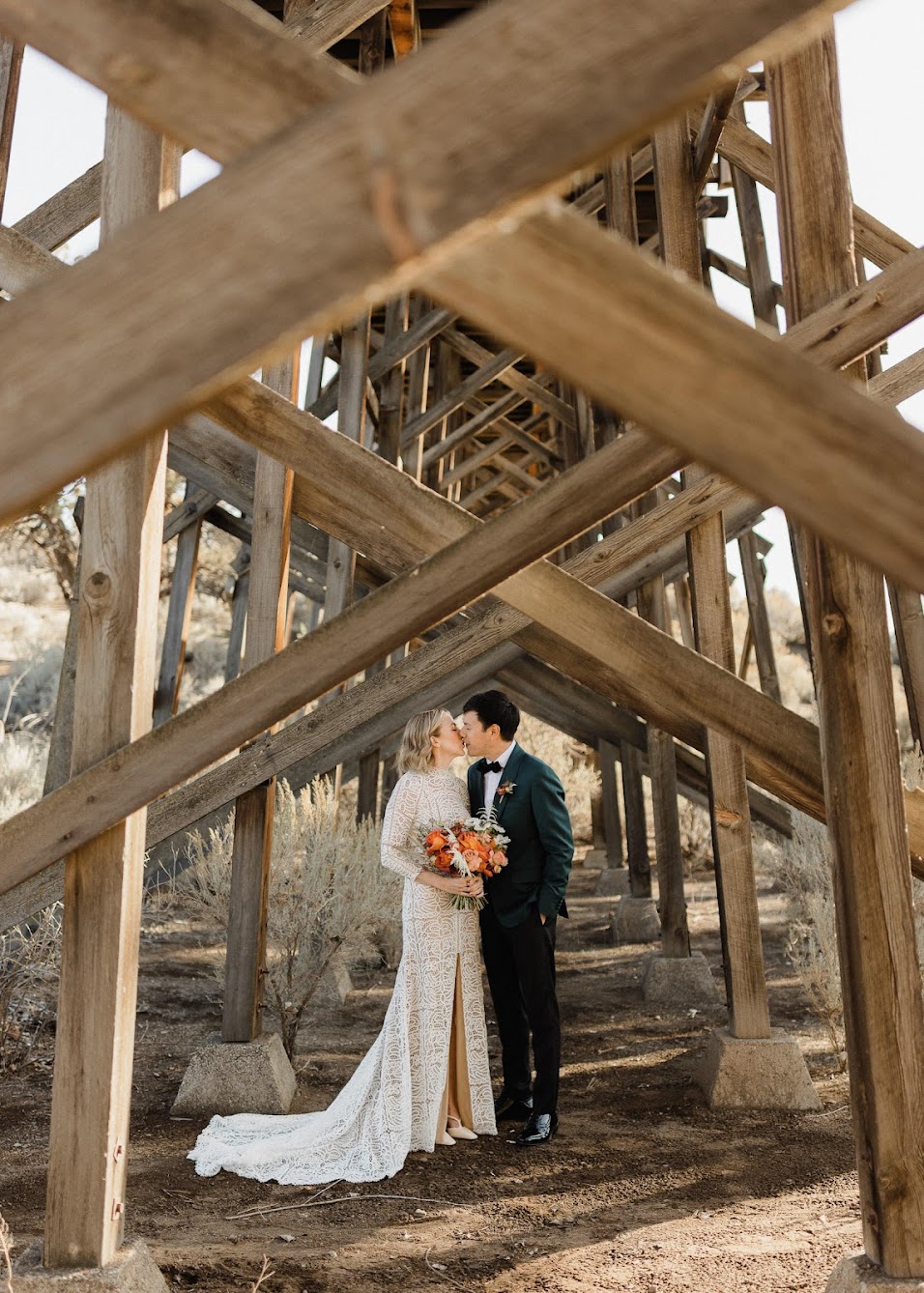 Bride and groom kissing under the wooden bridge  at Brasada Ranch.