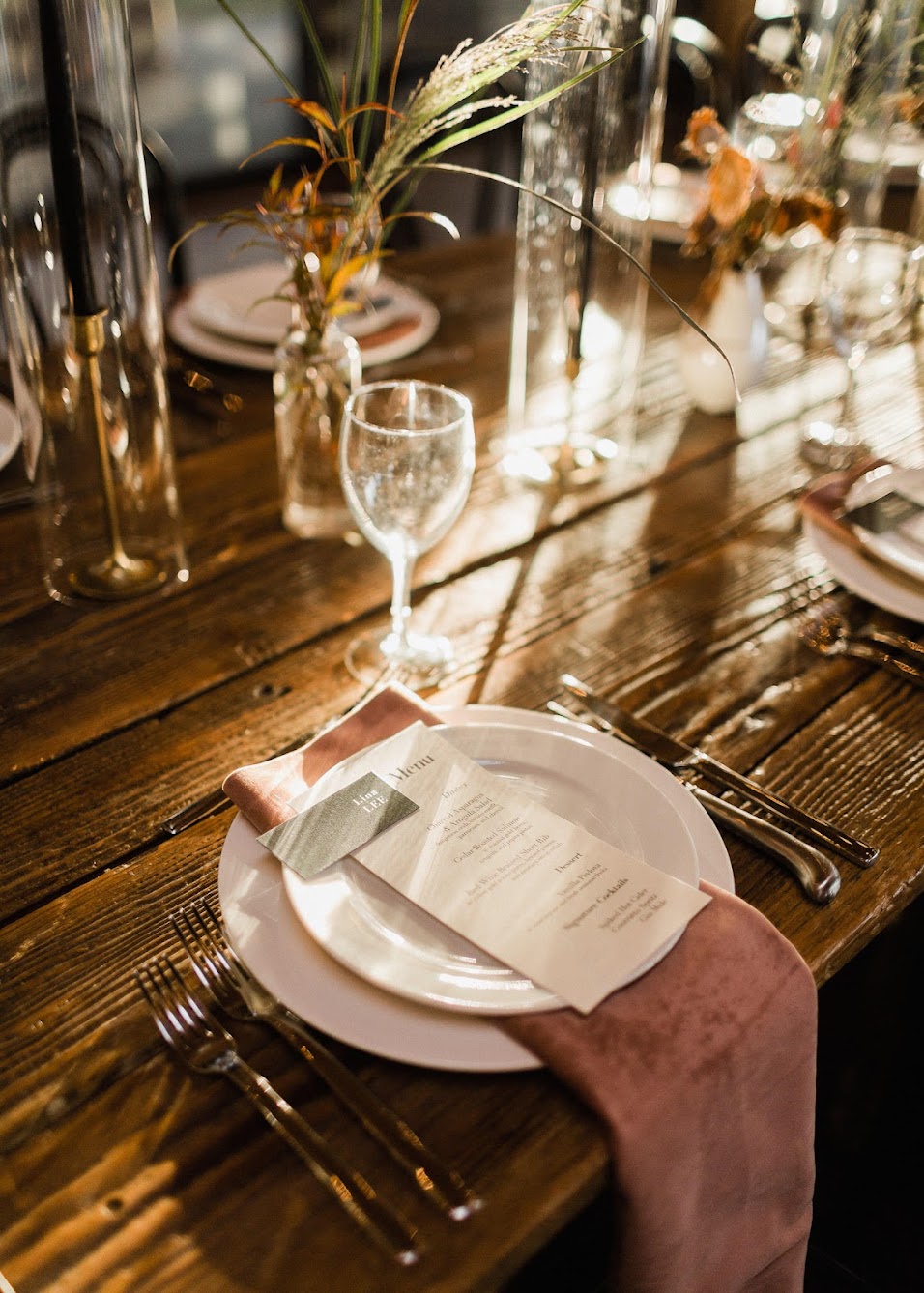 The place setting for guests. A velvet napkin sits between a dinner and salad plate. On top of the salad plate sits a dinner menu and a name card.