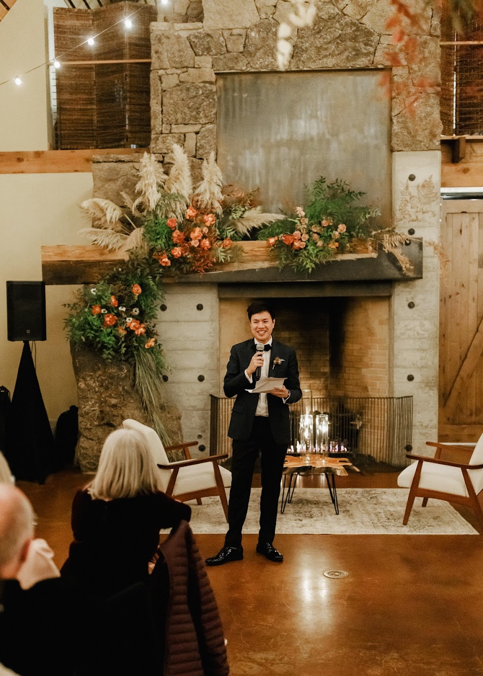 The groom standing in front of the fireplace giving a speech.