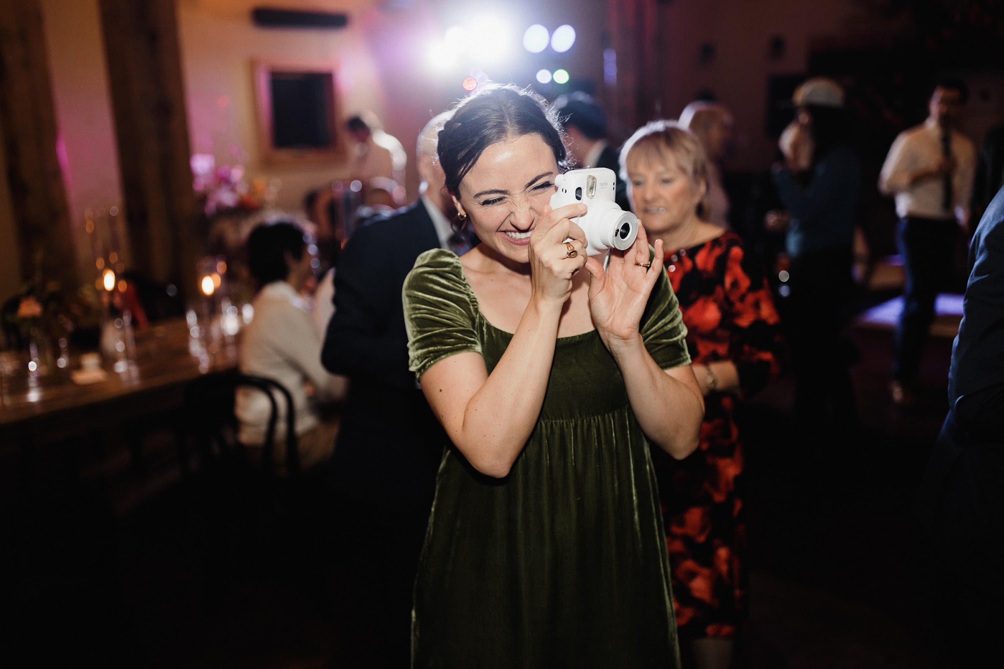 bridesmaid holding a polaroid camera, taking a photo the bride