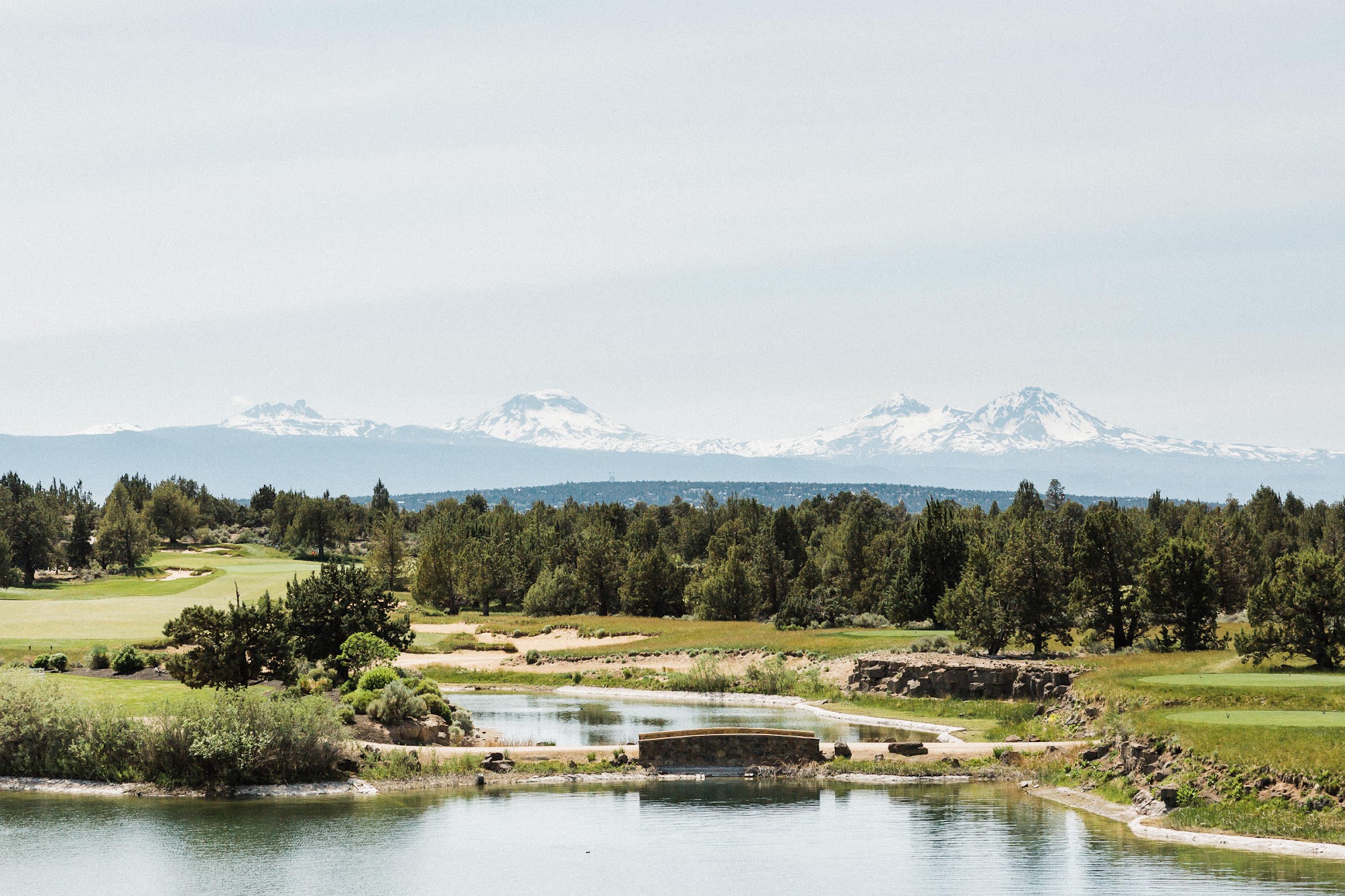 Pronghorn Resort's Event Island. It sits in the middle of a large pond that is surrounded by a golf course. The backdrop is a stunning mountain range, Broken Top, Mt. Bachelor and The Three Sisters. 