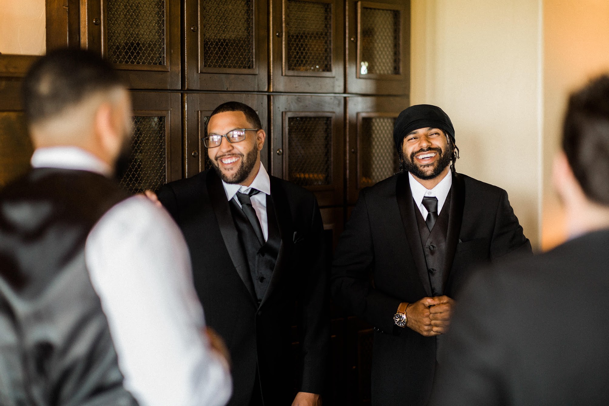 The groomsmen all standing around smiling with their black suites on. 