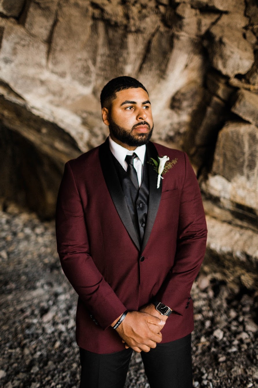 groom standing in a cave, where his ceremony is taking place. He has his arm folded and he is waiting for his soon to be wife.