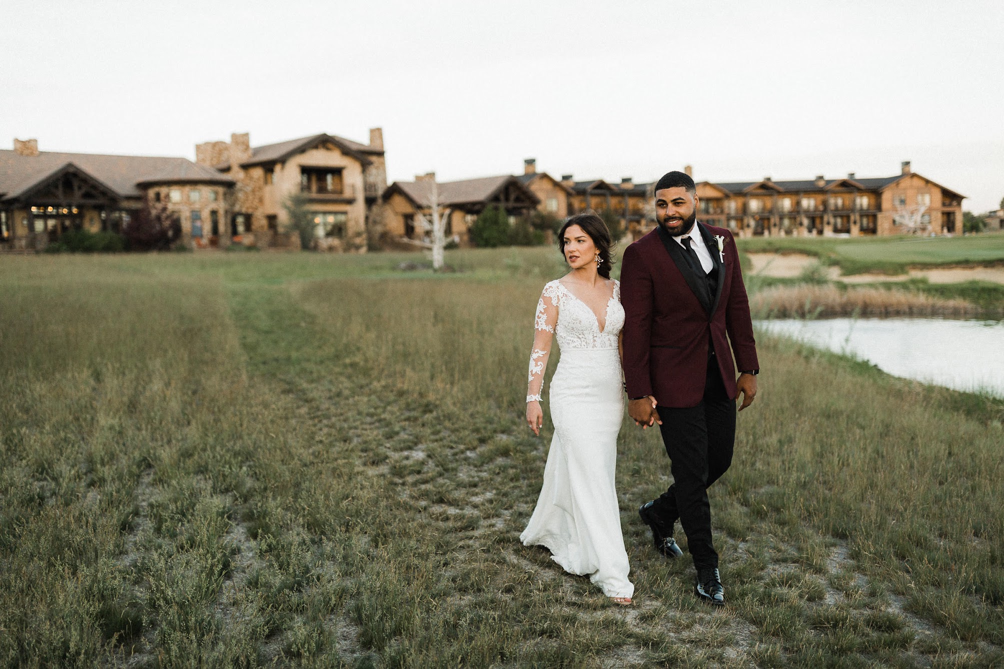 the couple walking with Pronghorn Resort, a stunning Tuscan like villa set behind them.