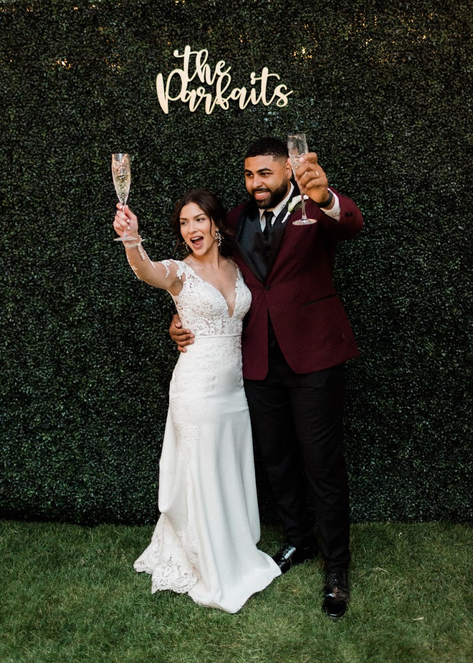couple holding a crystal champagne glasses up with one arm around each other 