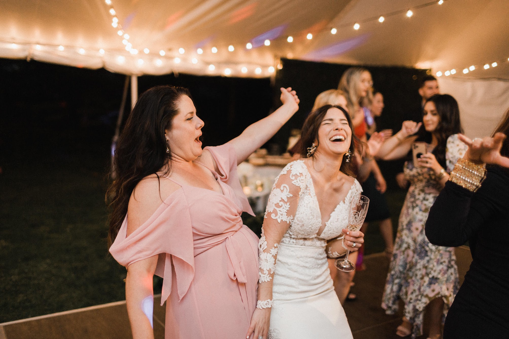 bride dancing with her maid of honor, bumping with hips together, laughing.