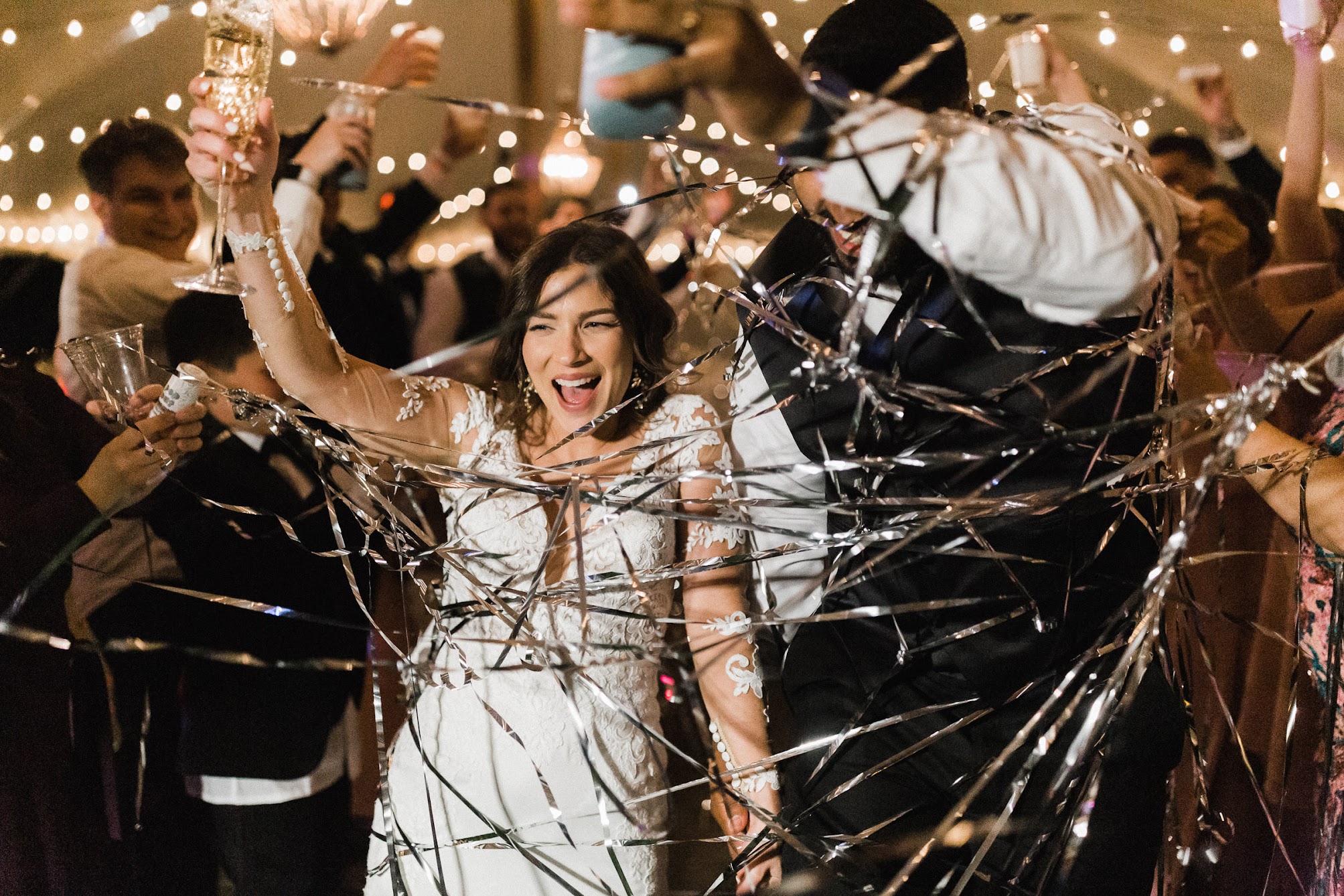 bride and groom walking through silver confetti string 