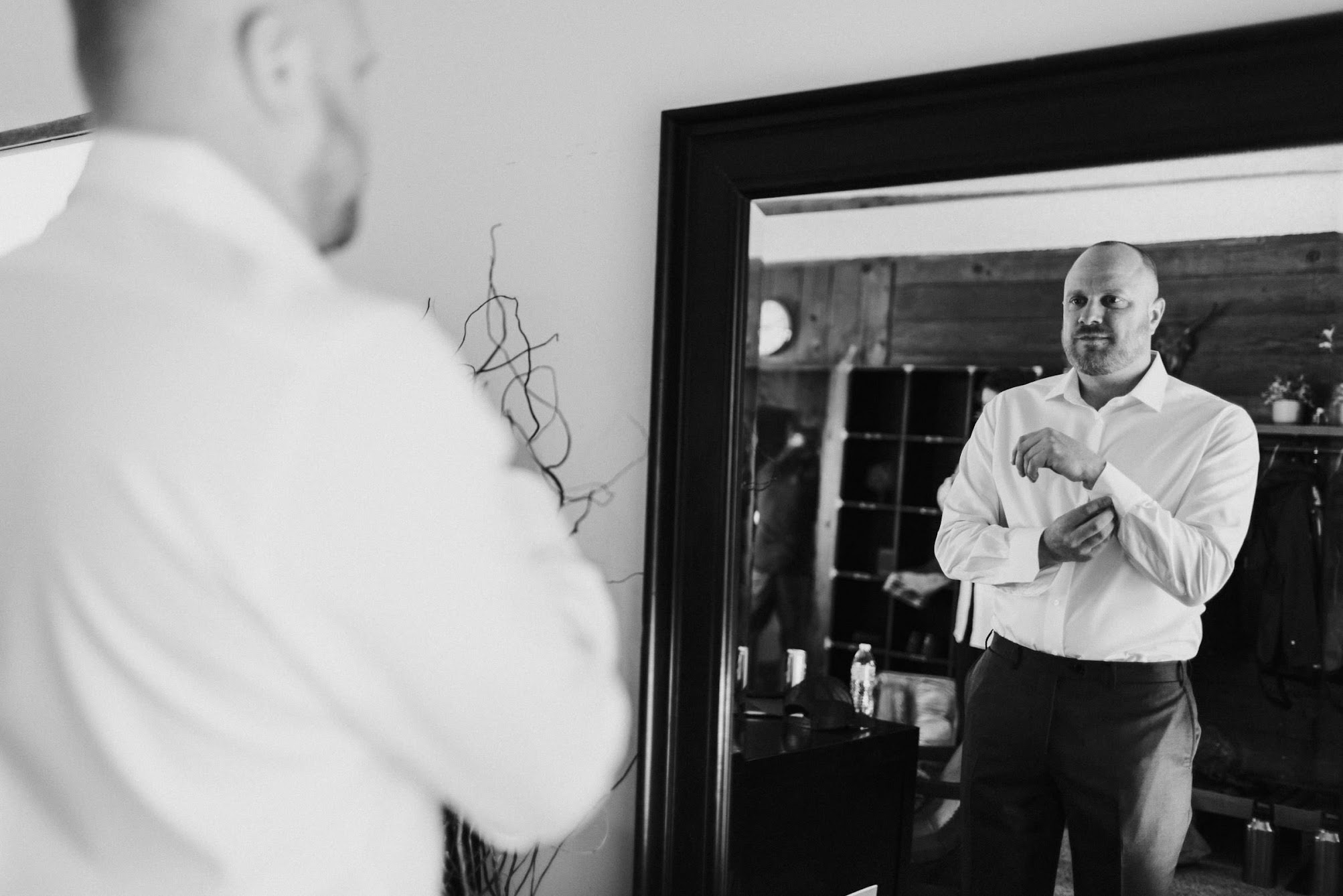The groom looking the mirror while he gets ready, fixing is collard shirt