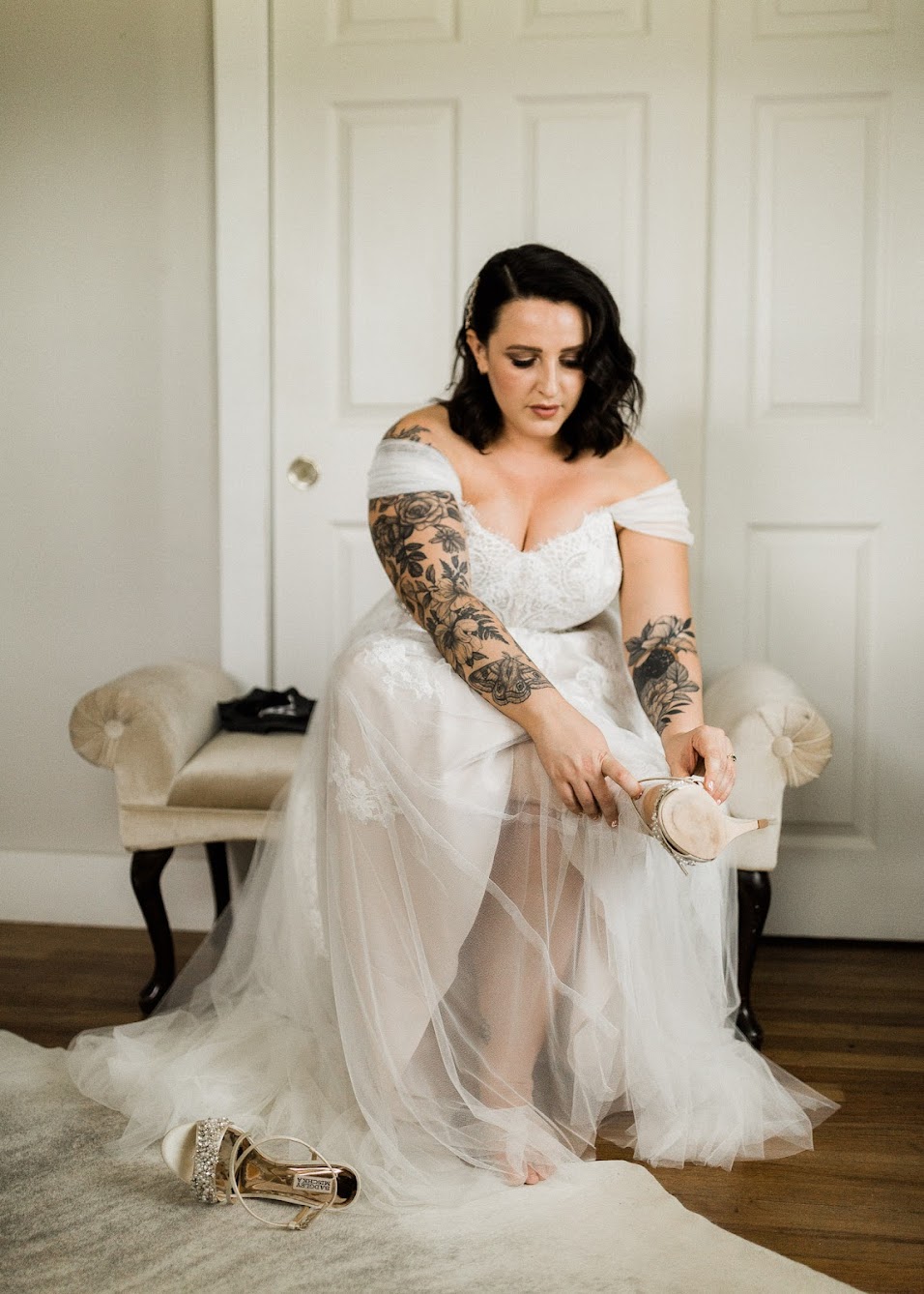 Bride sitting on a vintage bench while putting on her open-toed bridal shoes