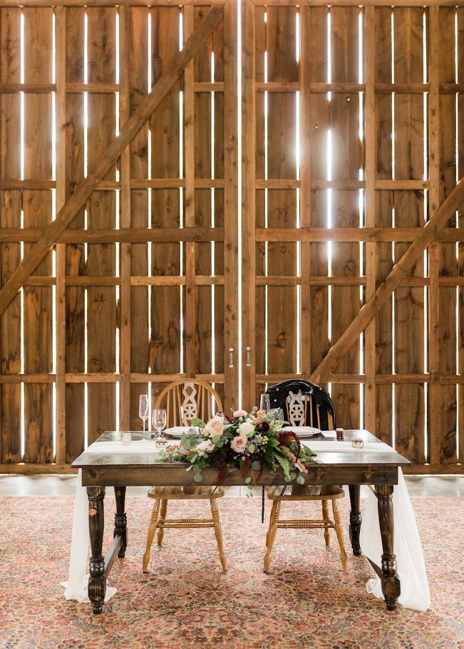 An antique wooden table set for the couple, always known as a sweetheart table. The bride's bouquet sits in the middle of the table.
