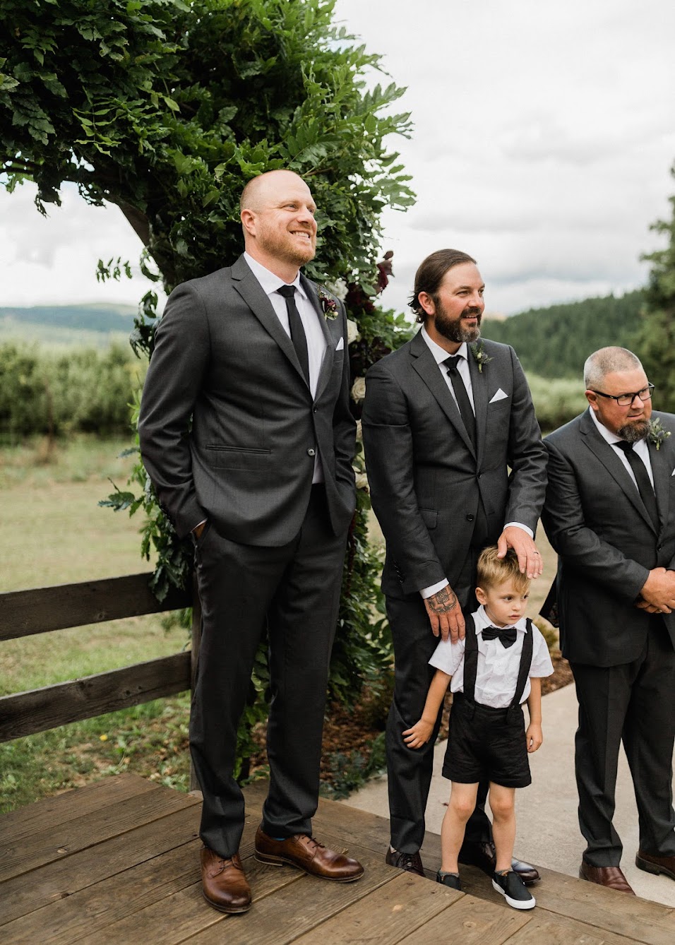 The groom and his groomsmen all smiling as they watch the bride come down the aisle.