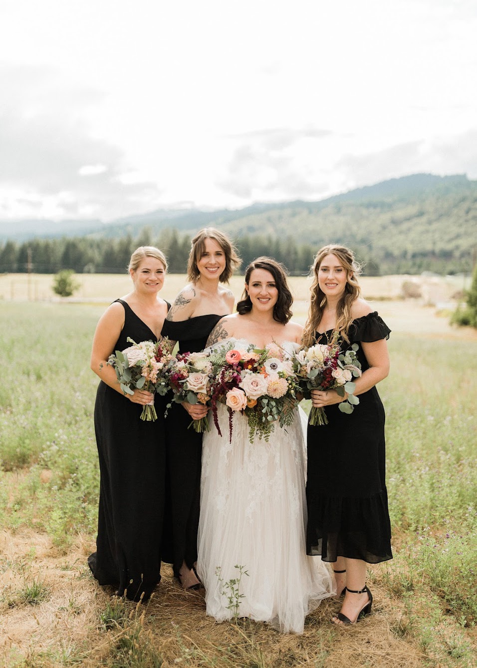 The bride and her bridesmaids are standing close to each other.  