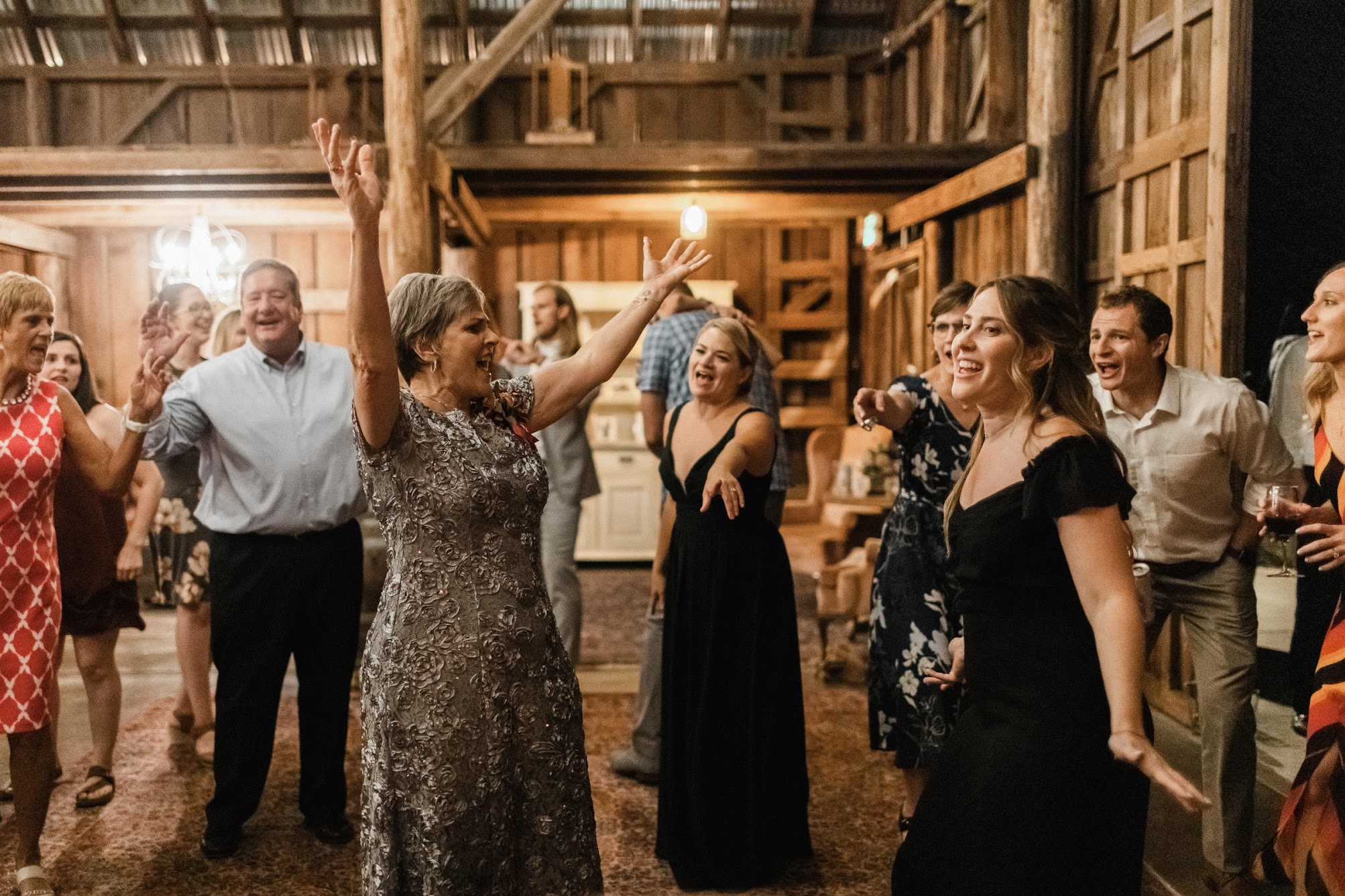 Mother of the bride and bridesmaid dancing together while everyone else watches and signs along.